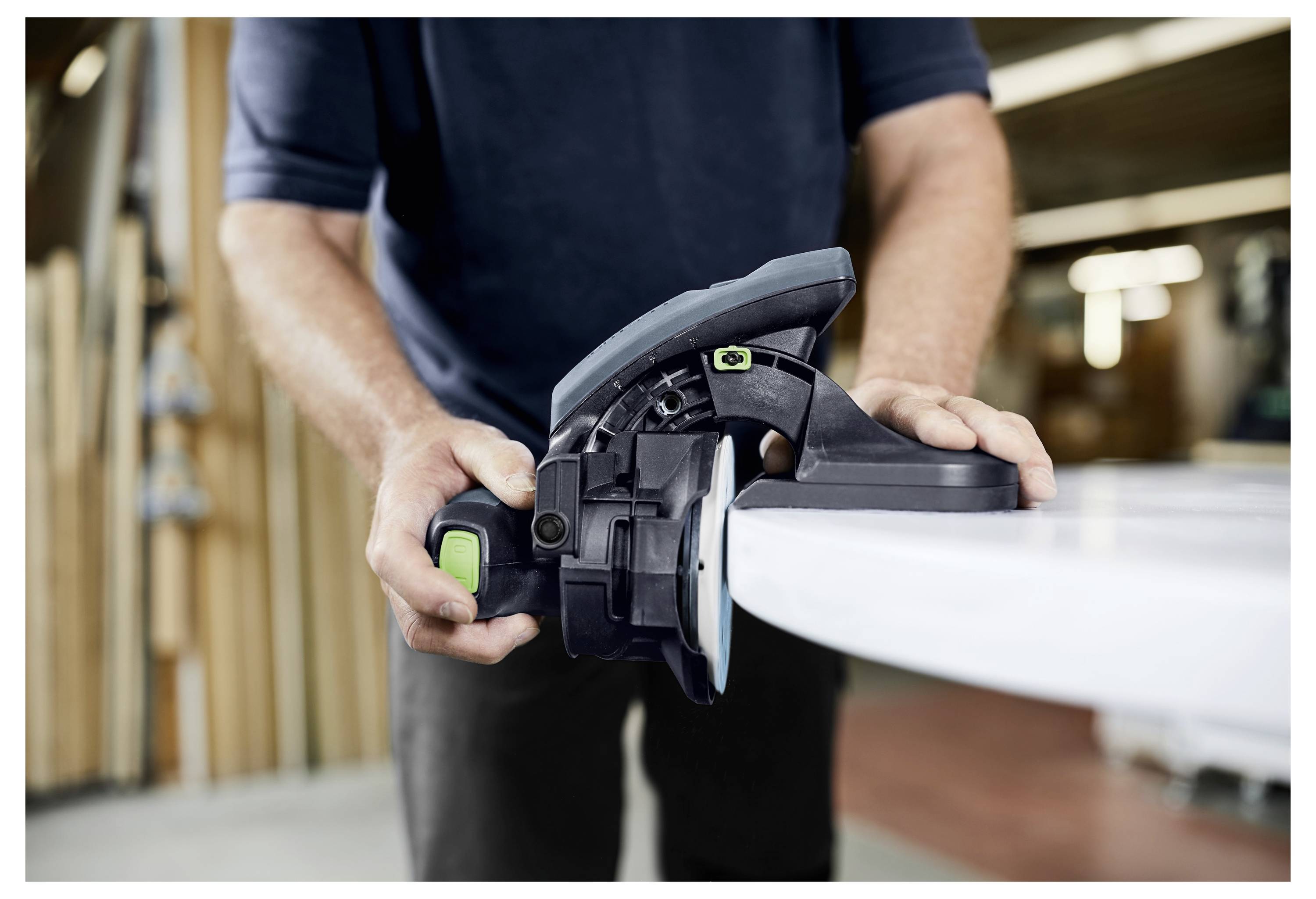 Osoba koristi kružnu pilu za rezanje drvene daske u radionici, fokusirajući se na alat i radnju.