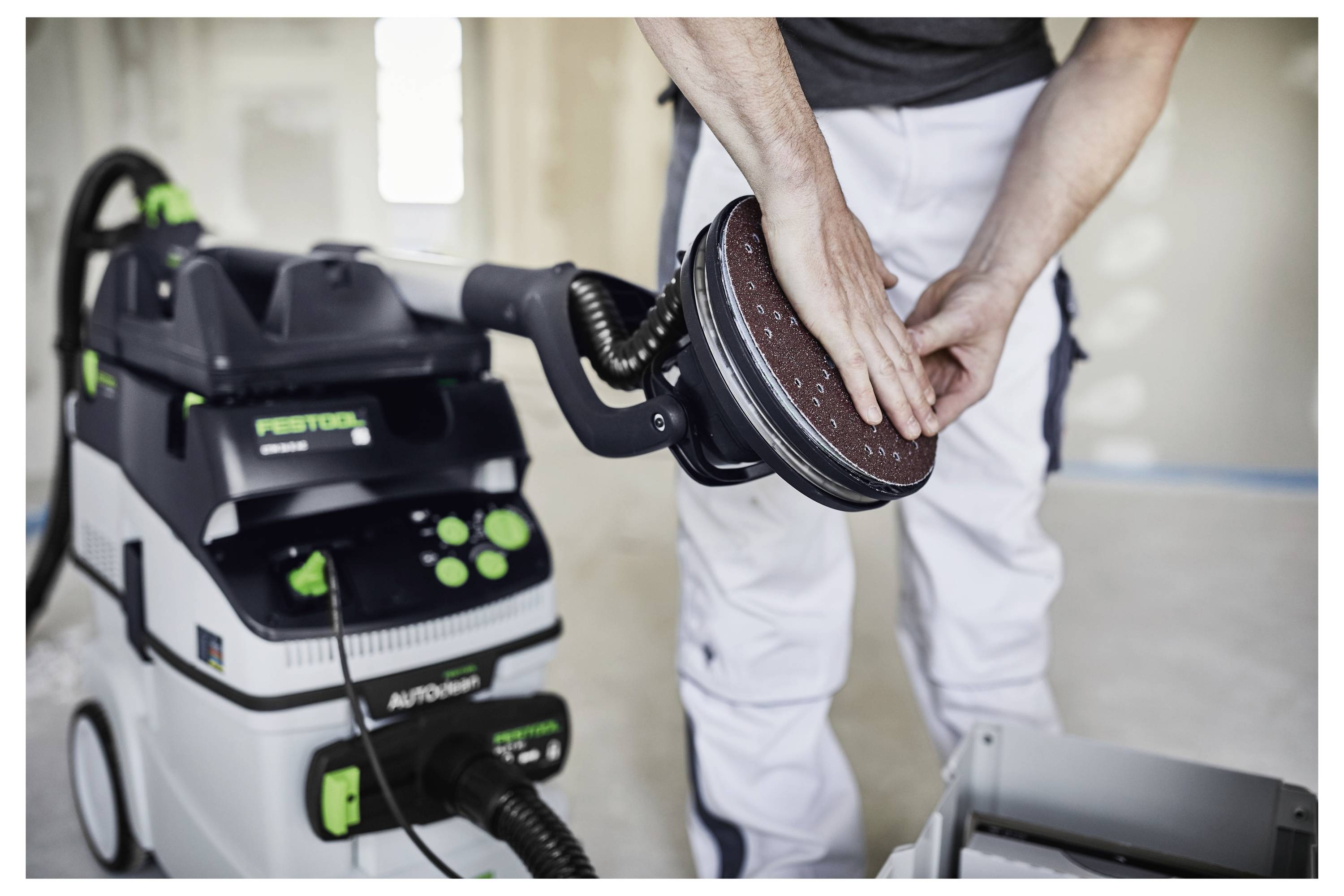 Osoba koristi električni alat za rezanje da bi napravila otvor u drvenom panelu montiranom na zidu, vjerojatno se pripremajući za građevinske ili instalacijske radove.