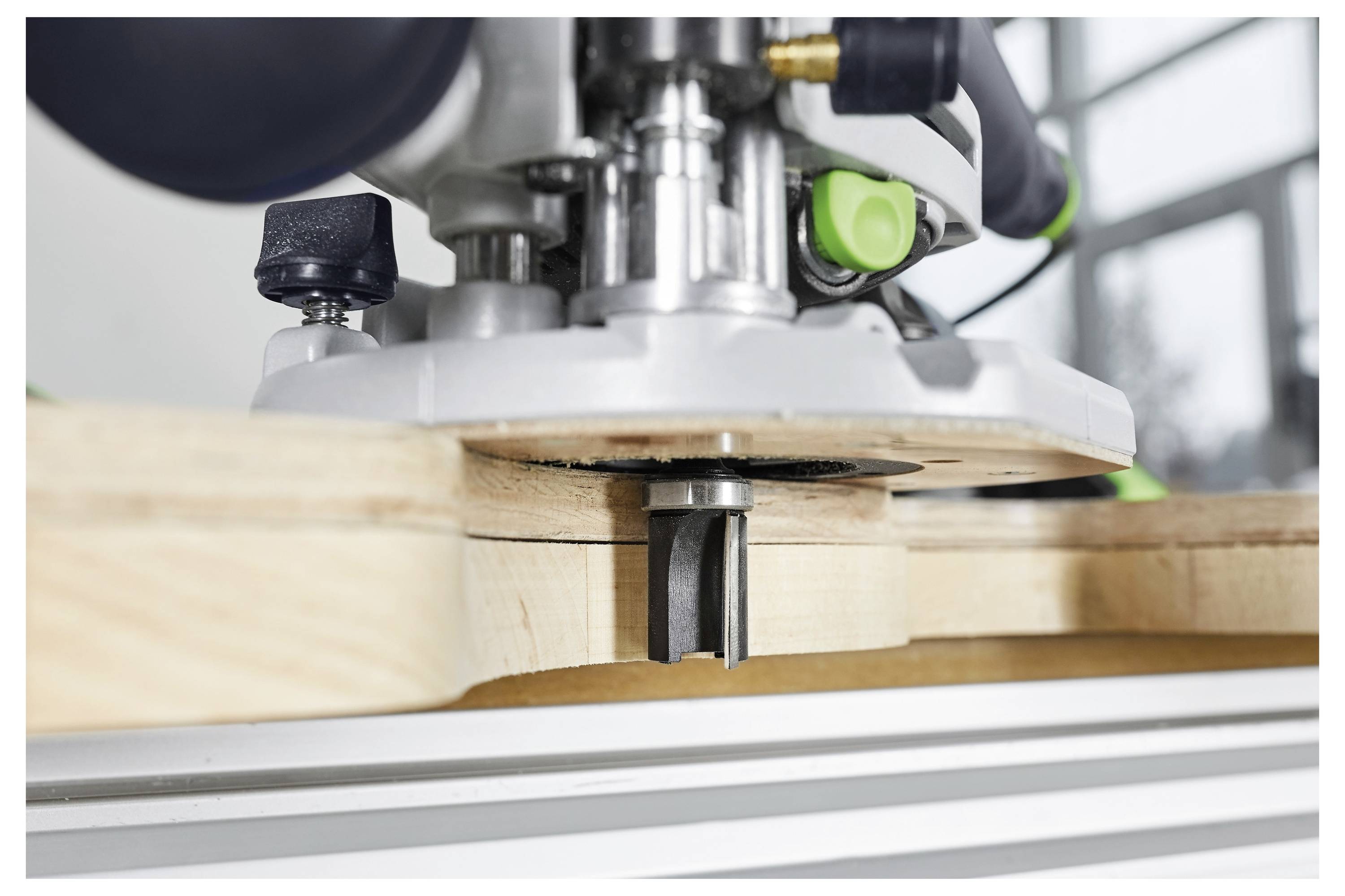 Detaljni prikaz tvorivca koji reže utor u drvenu dasku, s fokusom na metal bit i preciznost stroja.