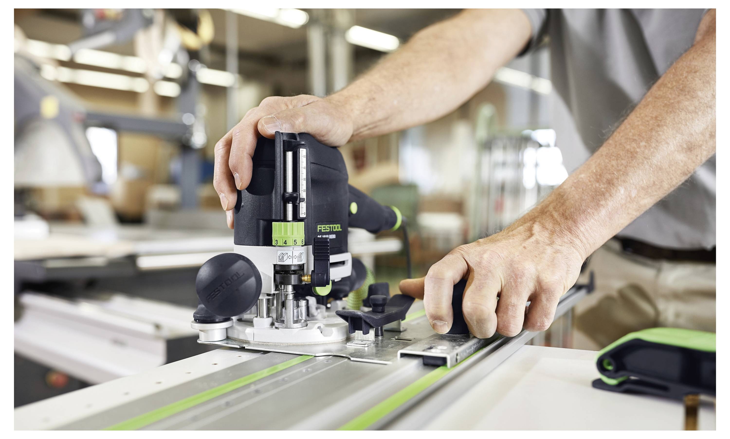 Osoba upravljaocem elektroalata na metalnoj šini u radioničkom okruženju, naglašavajući preciznost i majstorstvo u kontekstu obrade drva ili metala.