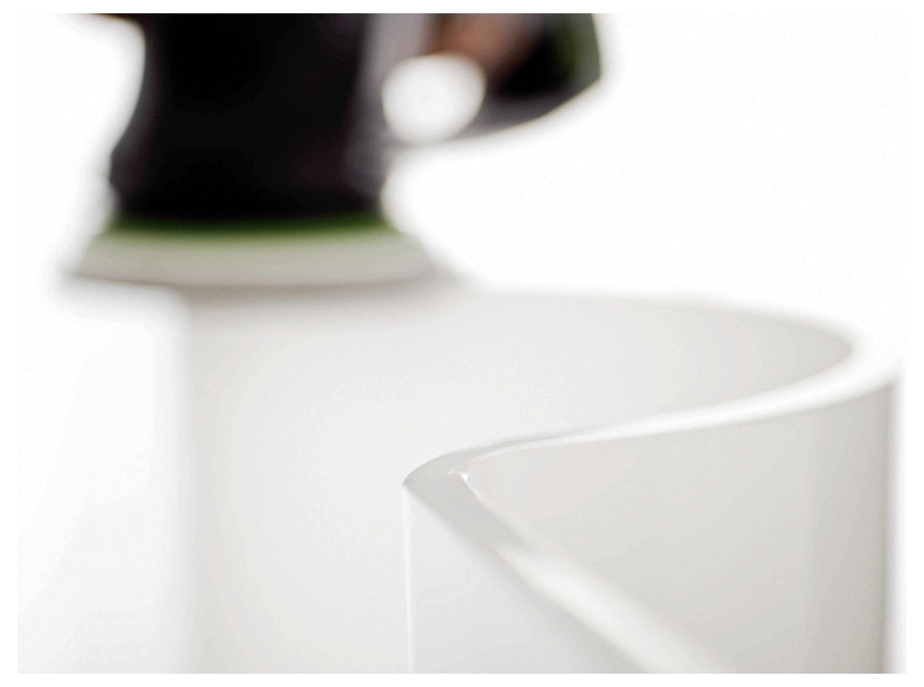 Detaljan prikaz zakrivljene, sjajne bijele površine koju u bluriranoj pozadini polira zamućeni alat, što sugeriše fokus na glatku završnu obradu.