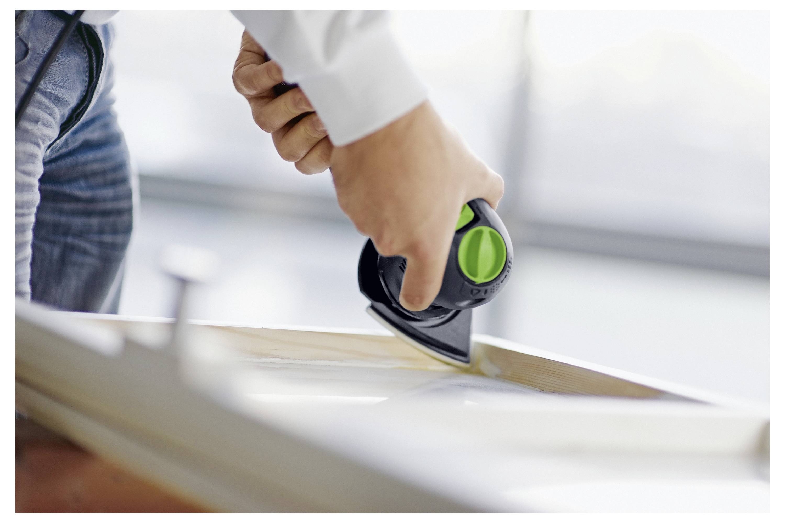 Osoba koja koristi ručni elektroalat za poliranje ruba drvene površine, fokusirajući se na preciznu i detaljnu работу.