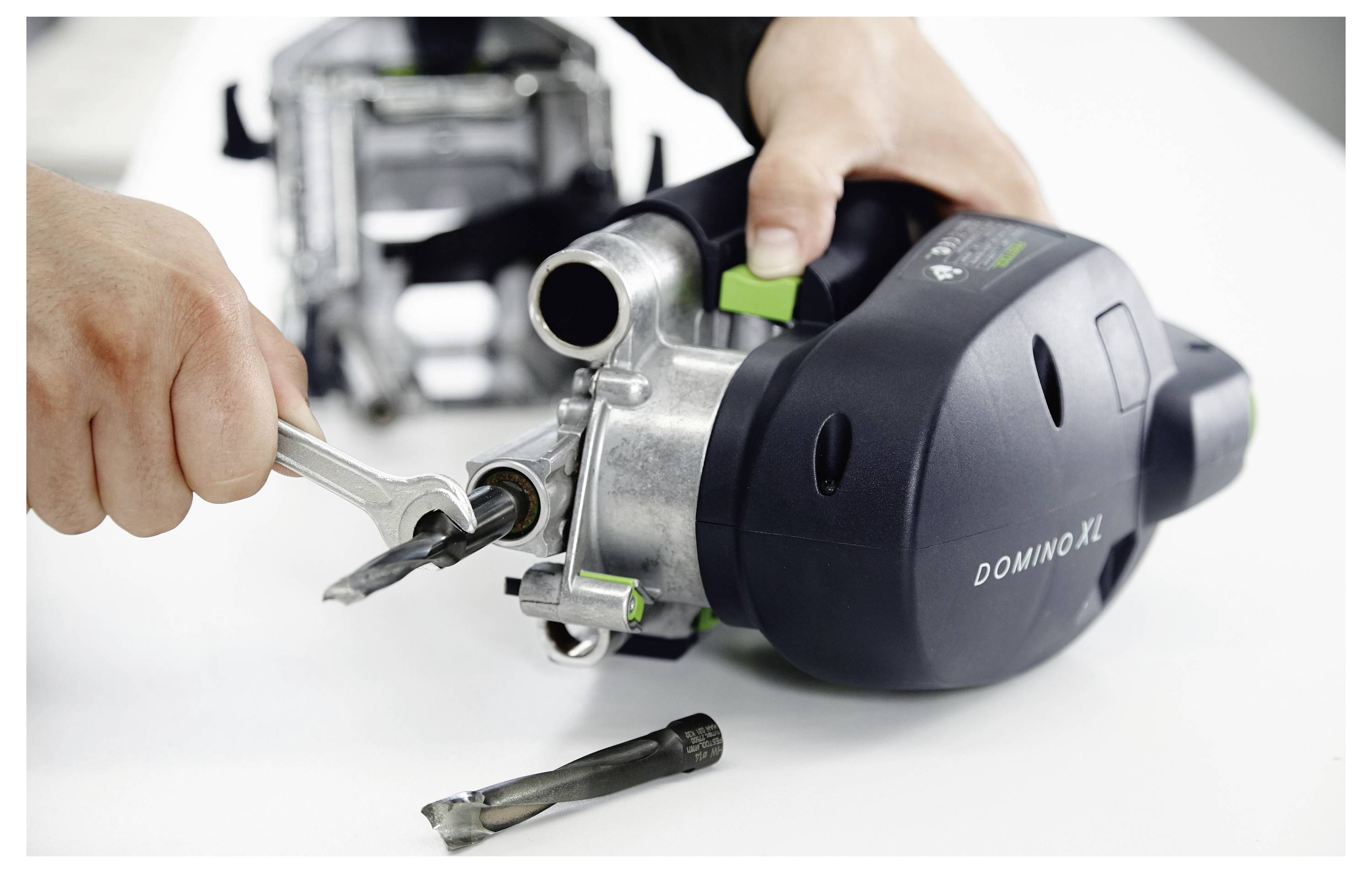 'Osoba podesava alat s ključem; u blizini su vidljivi svrdlo i tekst "DOMINO XL" na stroju, što ukazuje na njegov model.'