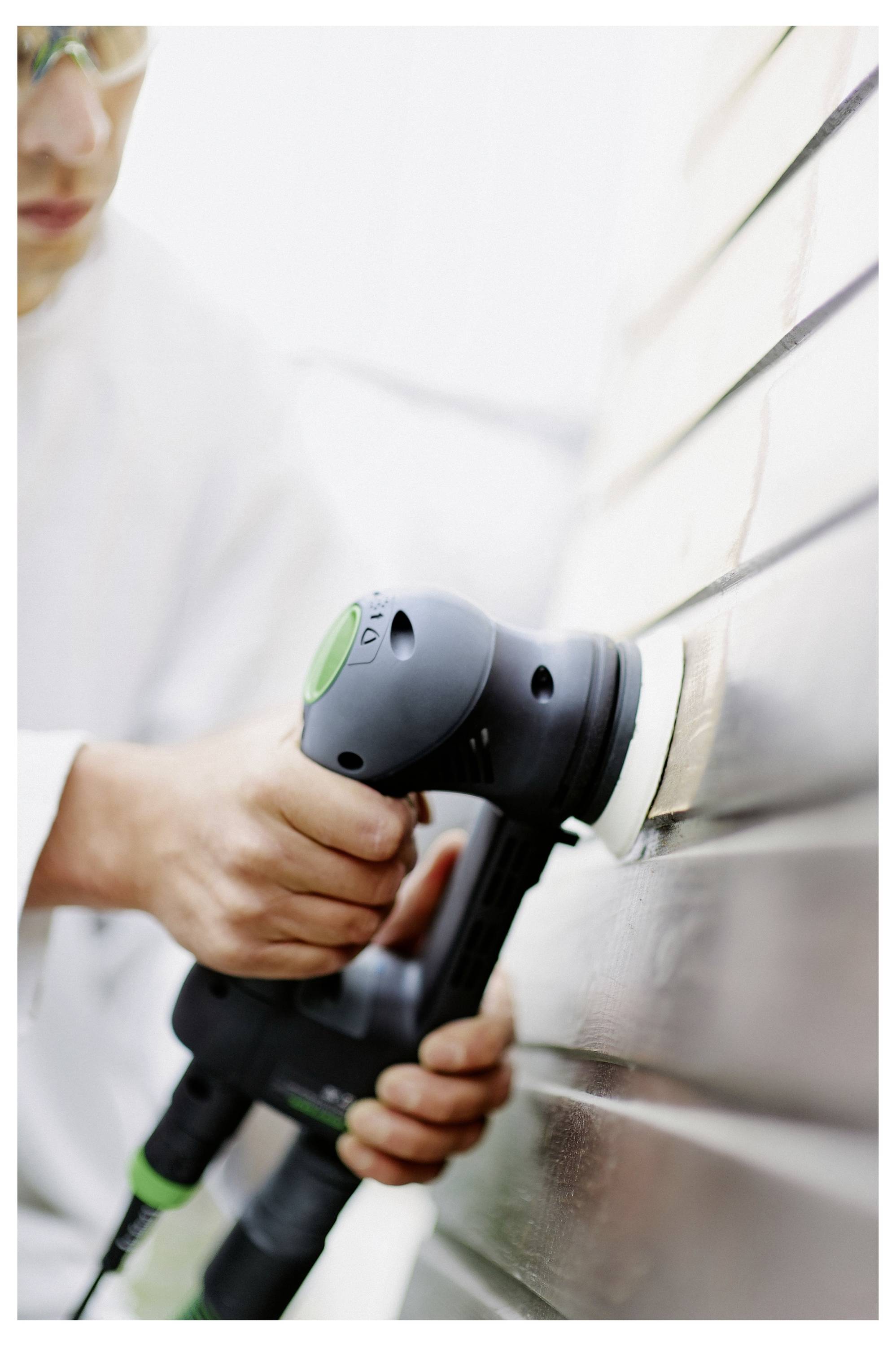 Osoba u zaštitnim naočalama koristi električni alat za poliranje drvene površine, fokusirajući se na postizanje glatke i sjajne završne obrade.