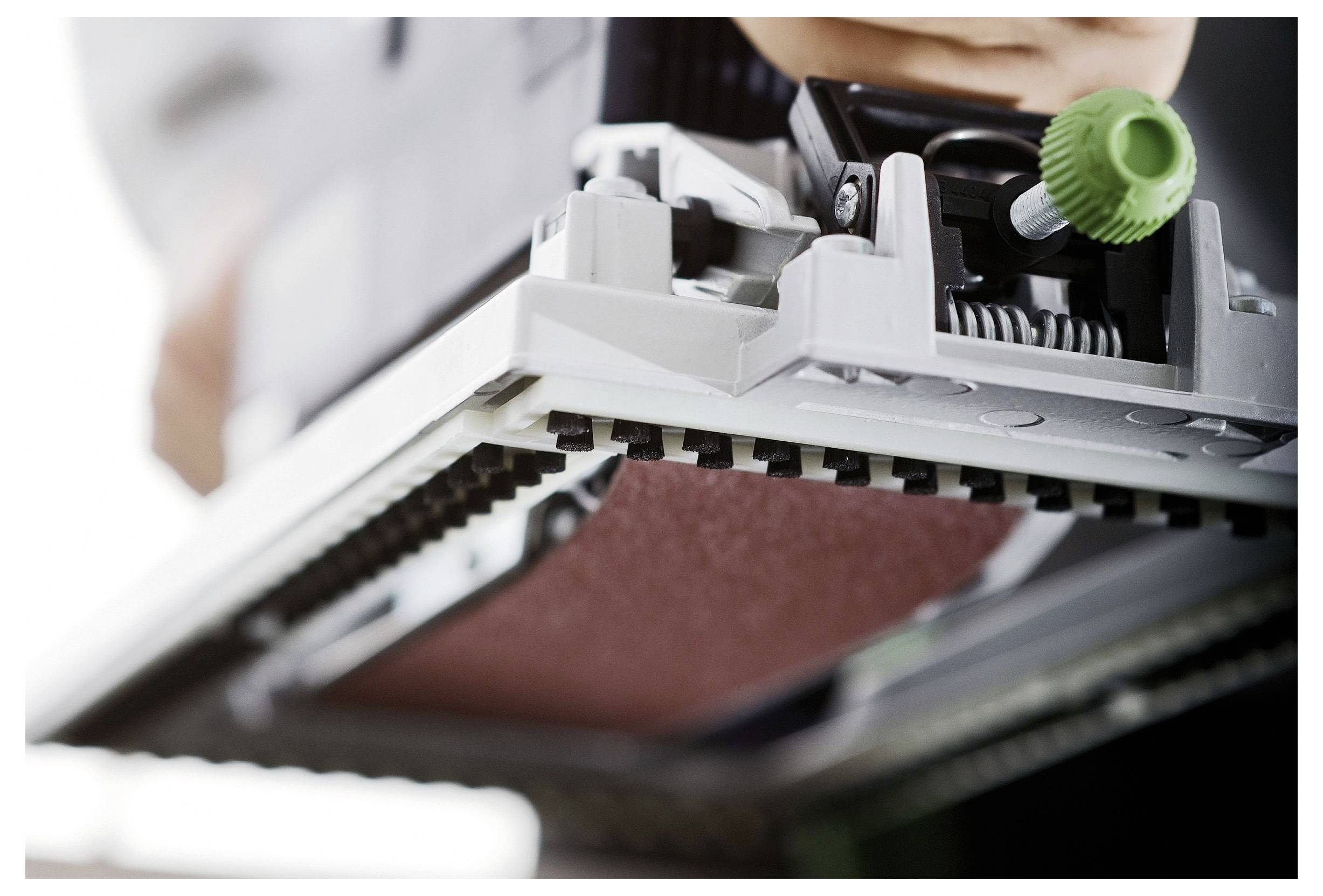 Detaljan prikaz stroja za brušenje u radu, prikazujući brušnu ploču i regulacijski gumb. Slika se fokusira na mehaniku i preciznost.