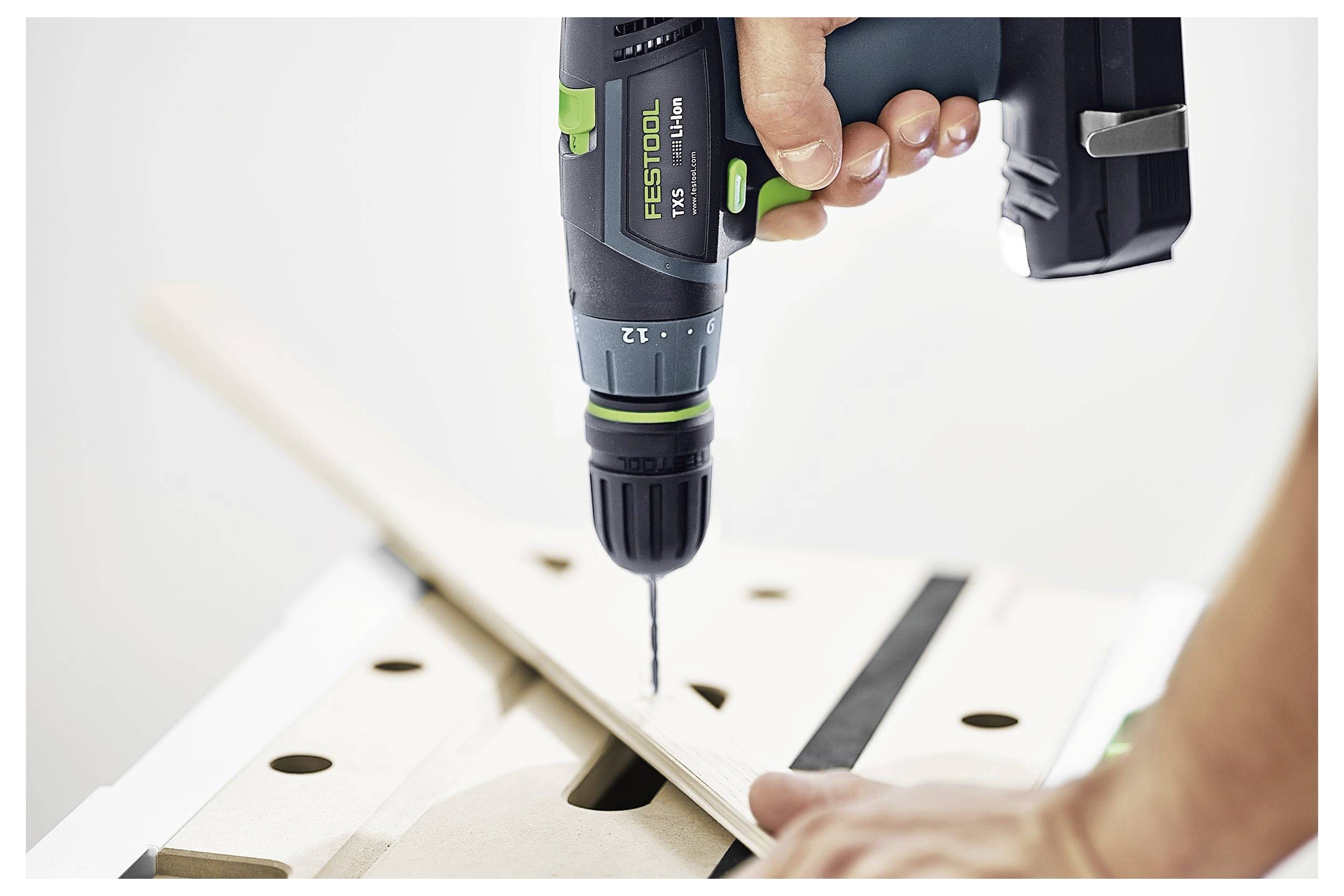 Osoba koristi bežičnu bušilicu kako bi napravila rupu u komadu drva na radnoj površini, čime pokazuje primjenu alata u stolarstvu.