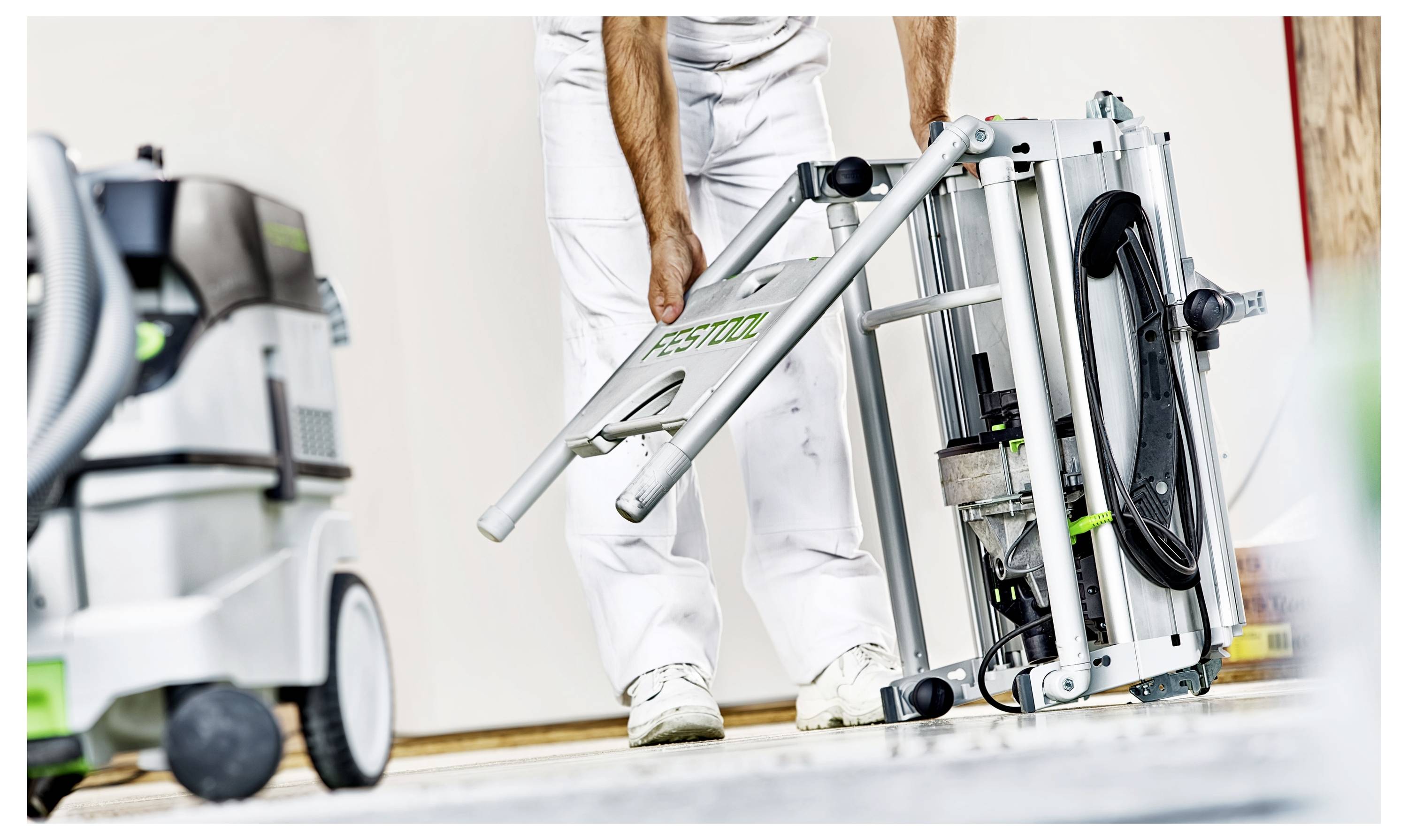 Osoba u radnoj odjeći postavlja industrijsku opremu, s fokusom na elektroalat koji ima logotip marke, pored vakuumskog sustava.