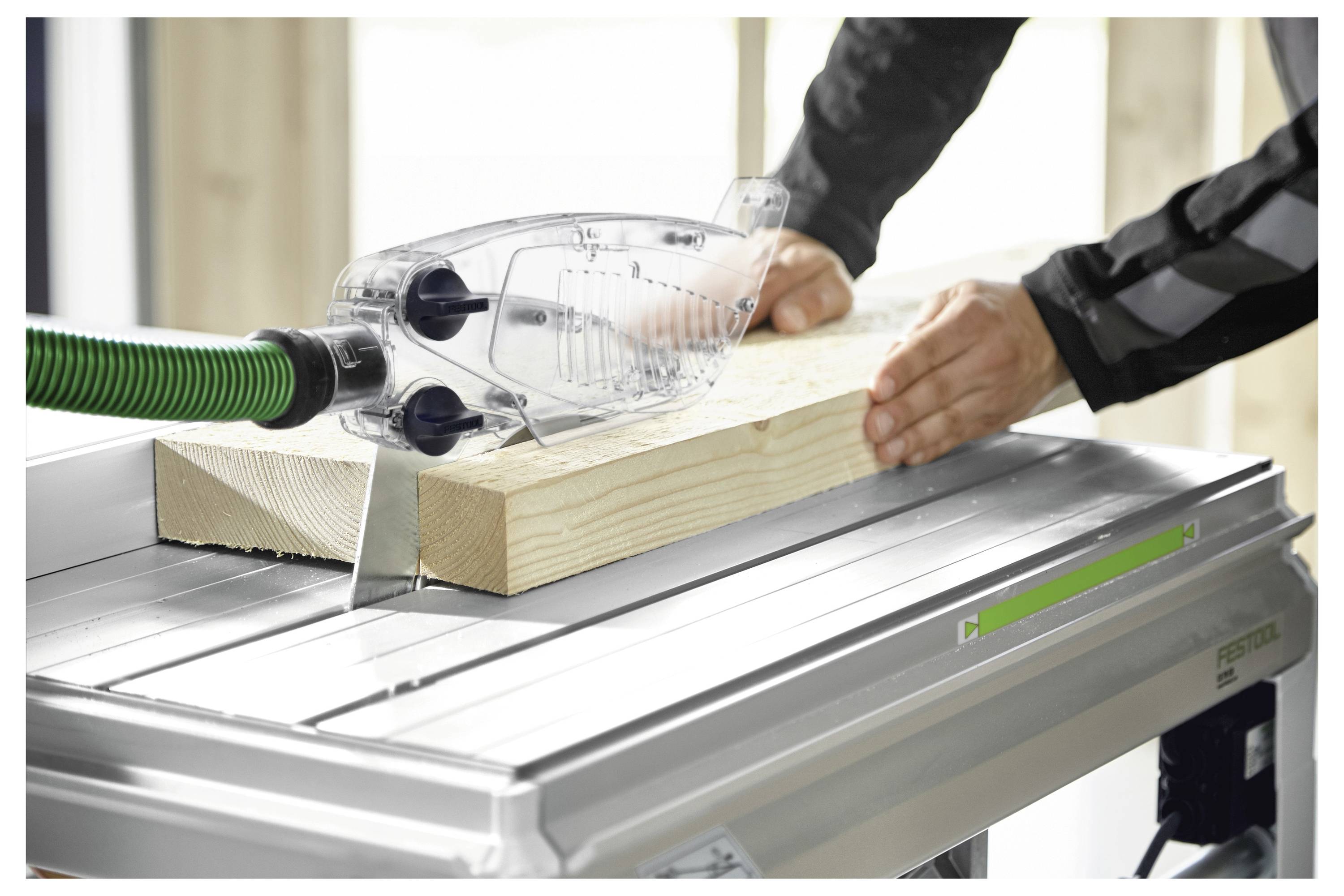 Osoba koristi električni tračni brusilica da ugladi rub drvene daske, ističući aktivnosti uključene u obradu drva.