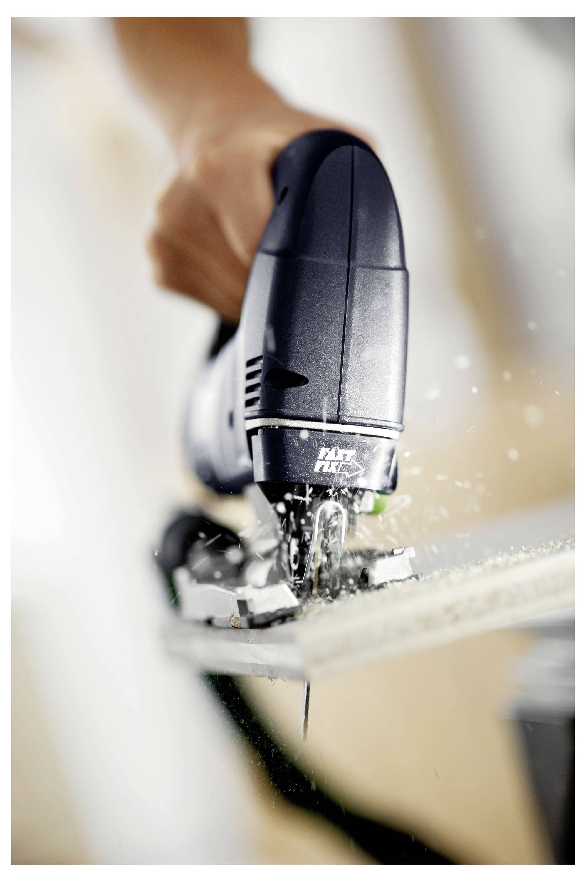 Ruka upravlja pila sa trakama koja precizno reže drvo, bacajući tračke drveta u zrak, što pokazuje stolarske alate u upotrebi.