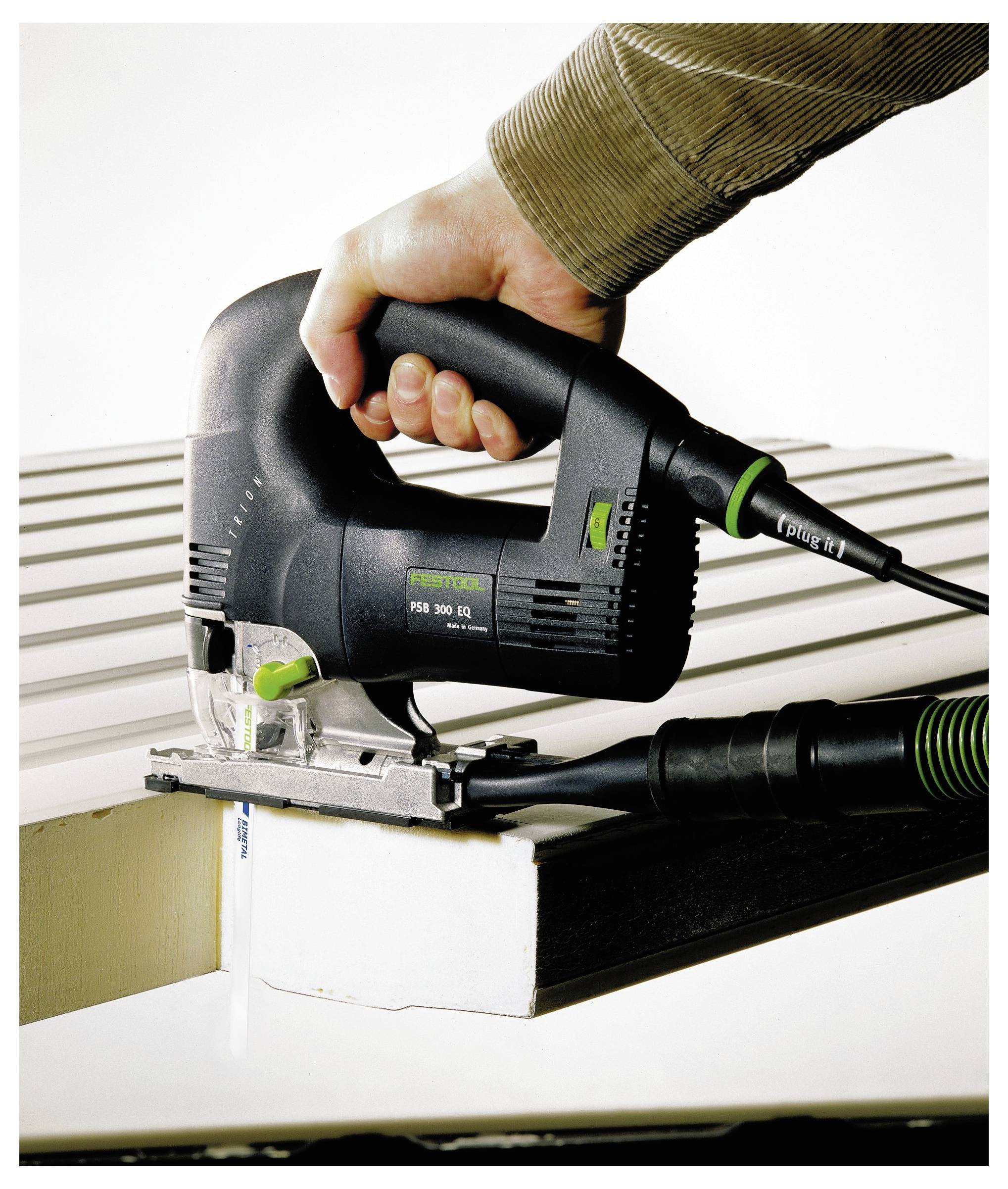 'Osoba koristi pilu za rezanje kako bi rezala komad materijala, demonstrirajući preciznost i kontrolu u DIY zadatku.'