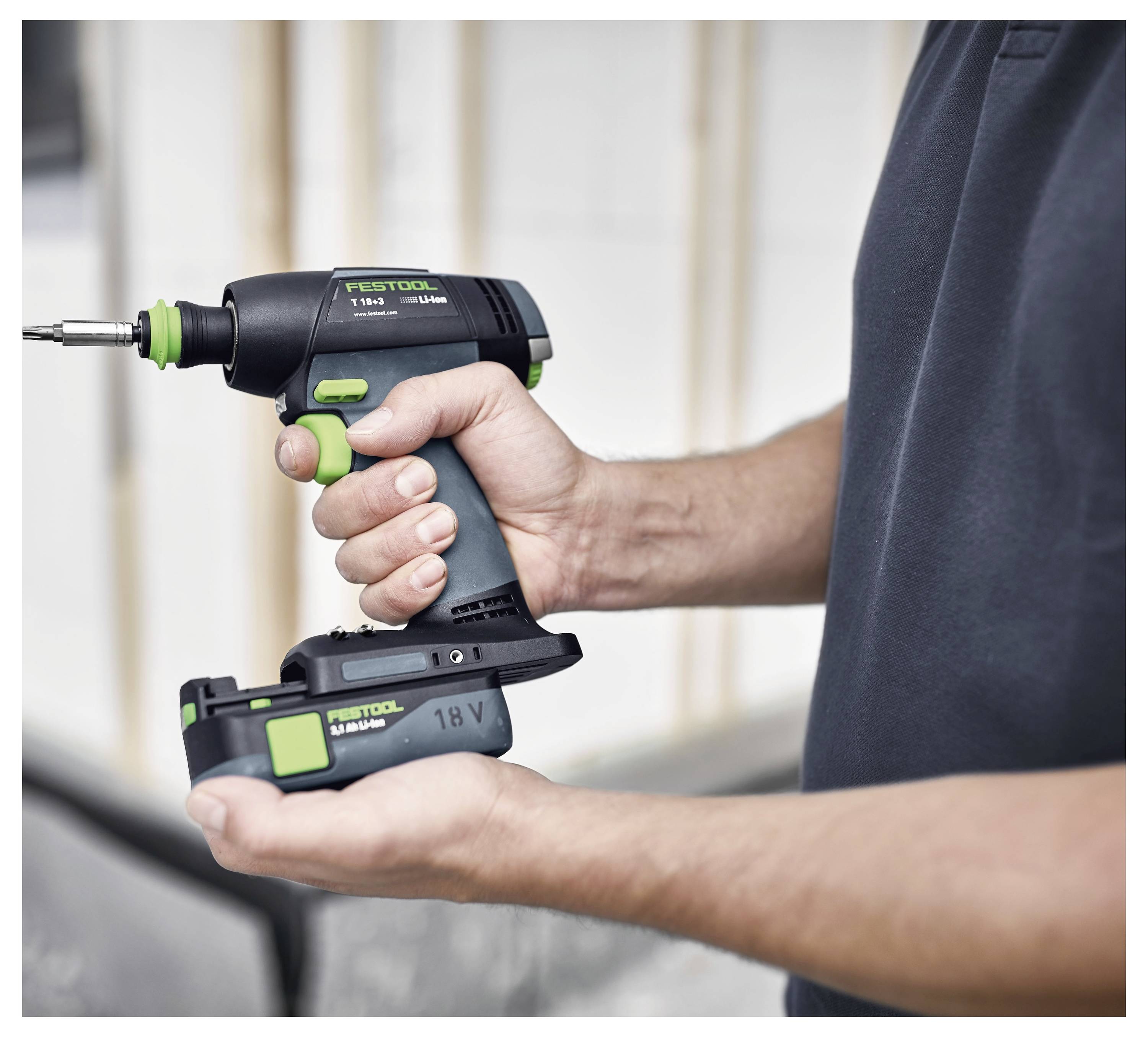 Osoba drži bežičnu bušilicu sa zelenim i crnim akcentima, označenu 'Festool 18V', spremnu za upotrebu, ističući njen ergonomski dizajn.