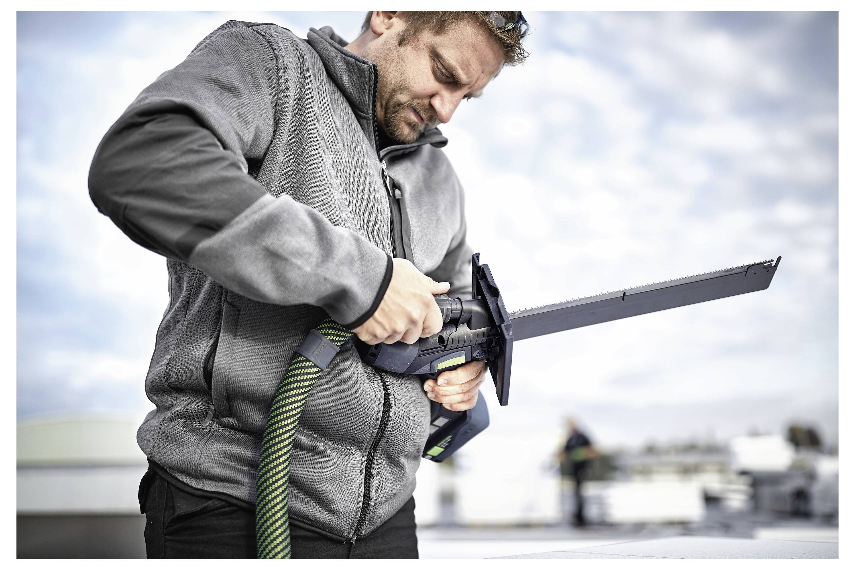 Osoba koristi ručnu električnu brusilicu na bijeloj drvnoj površini, fokusirajući se na zaglađivanje ili poliranje materijala.
