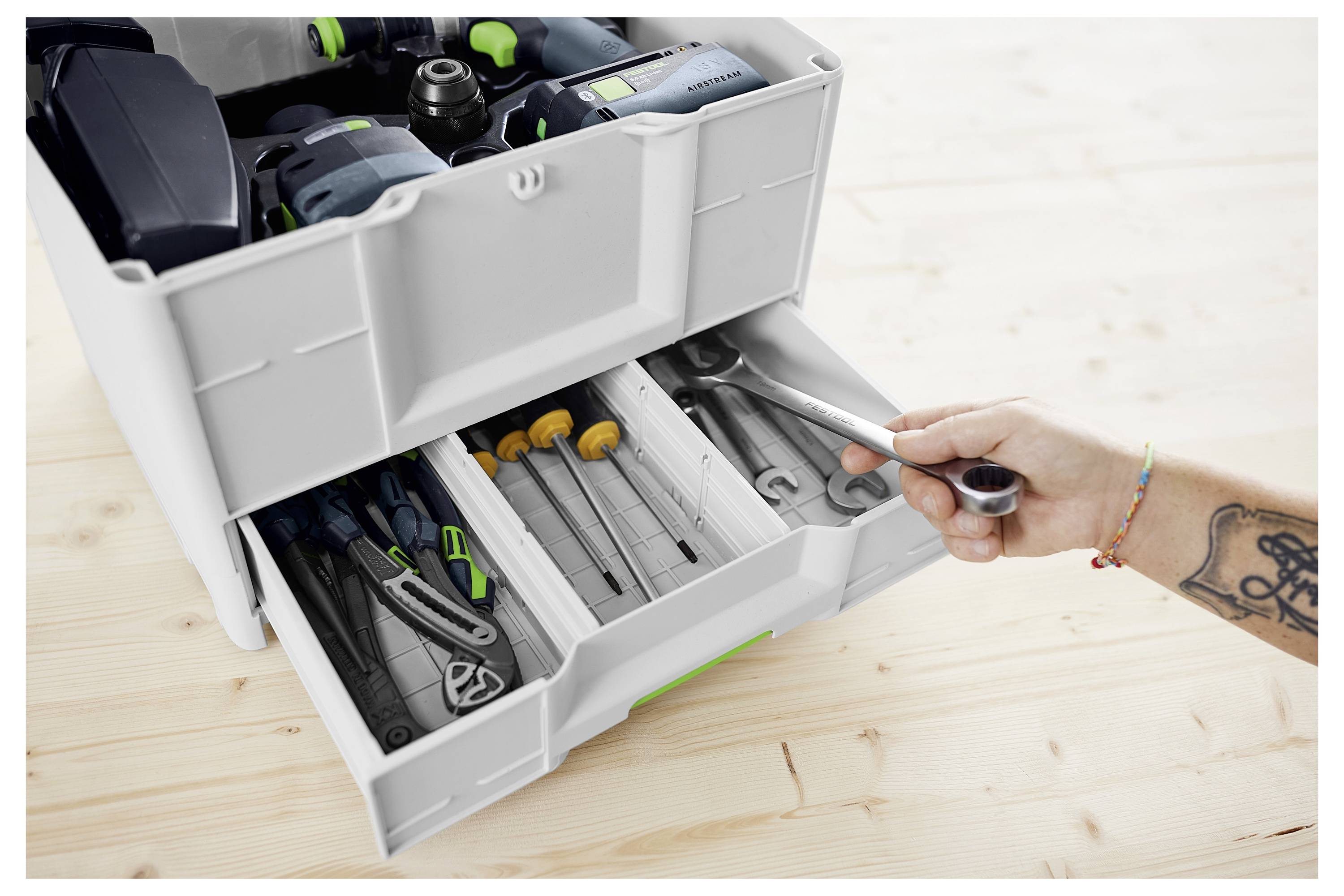 Osoba upravlja električnim alatom sa zelenom i crnom ručkom na sustavom traga, vjerojatno za precizno rezanje na površini.