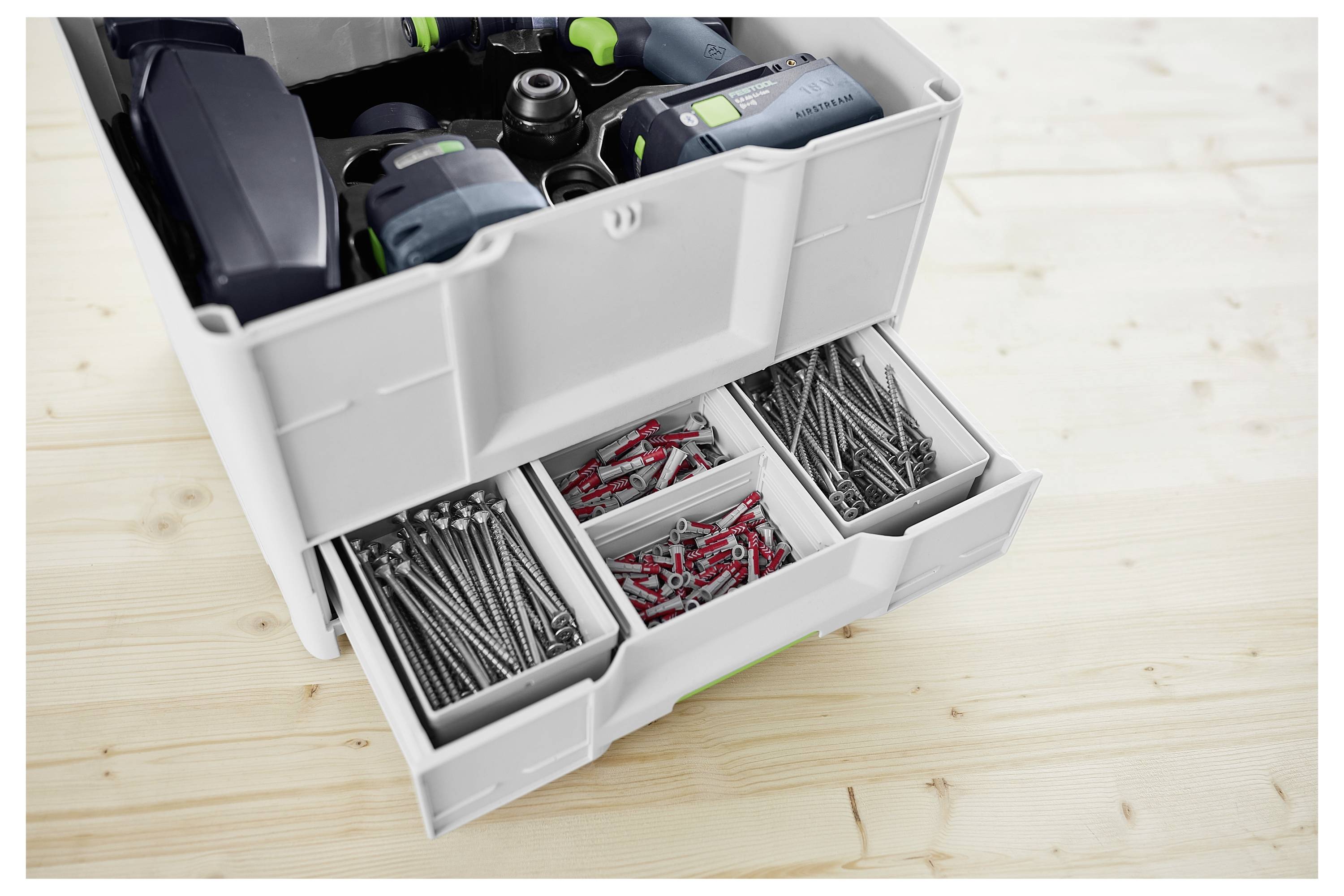 Skup alata unutar bijele sustava ladica na drvnoj površini. Gornja ladica sadrži električne alate, dok donje ladice sadrže vijke i sveexercise za bušenje.