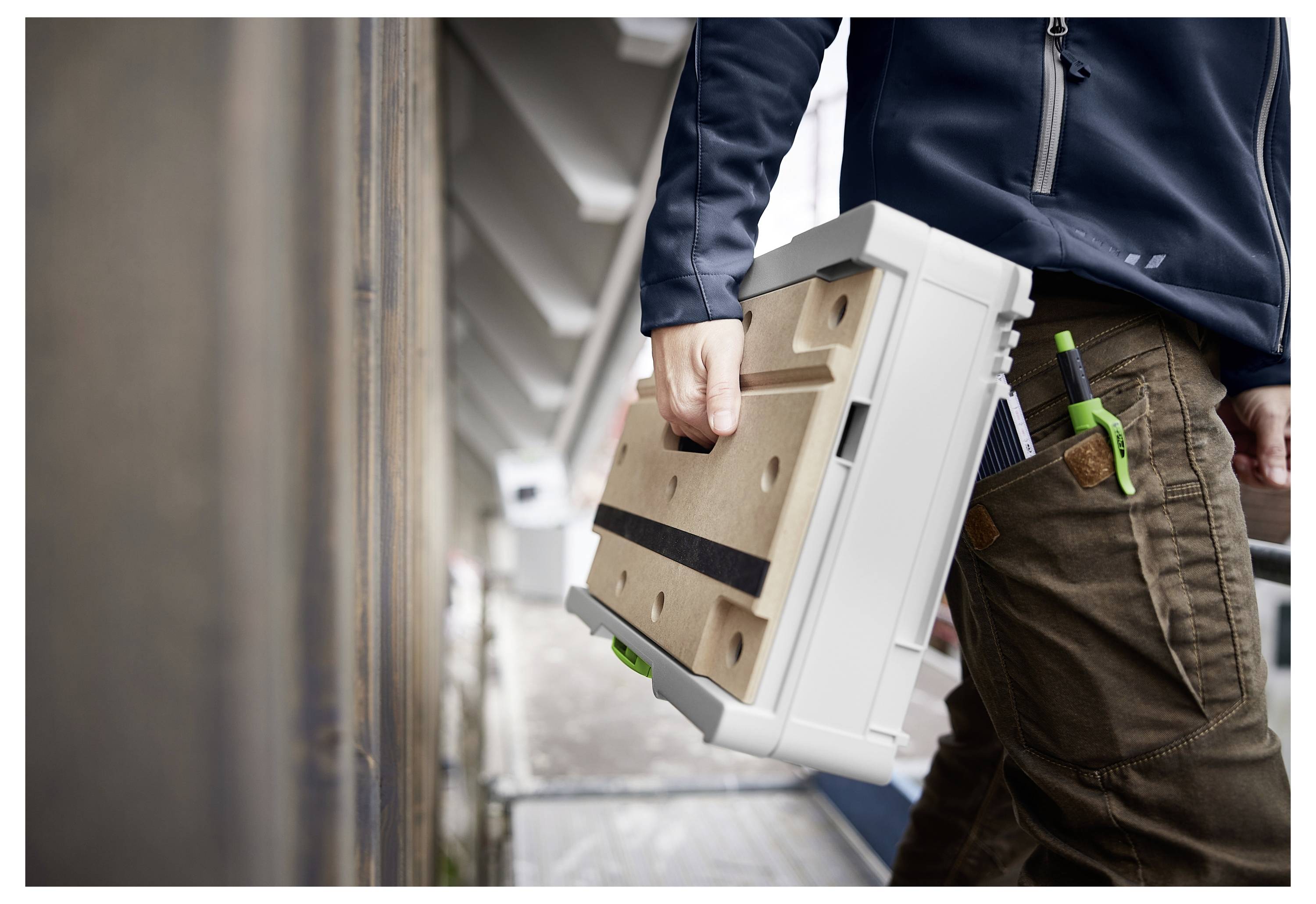 Osoba koja nosi zaštitne naočale rukuje motornom alatkom u radionici punoj drvenog namještaja i ormarića koji se nalaze u fazi izgradnje.