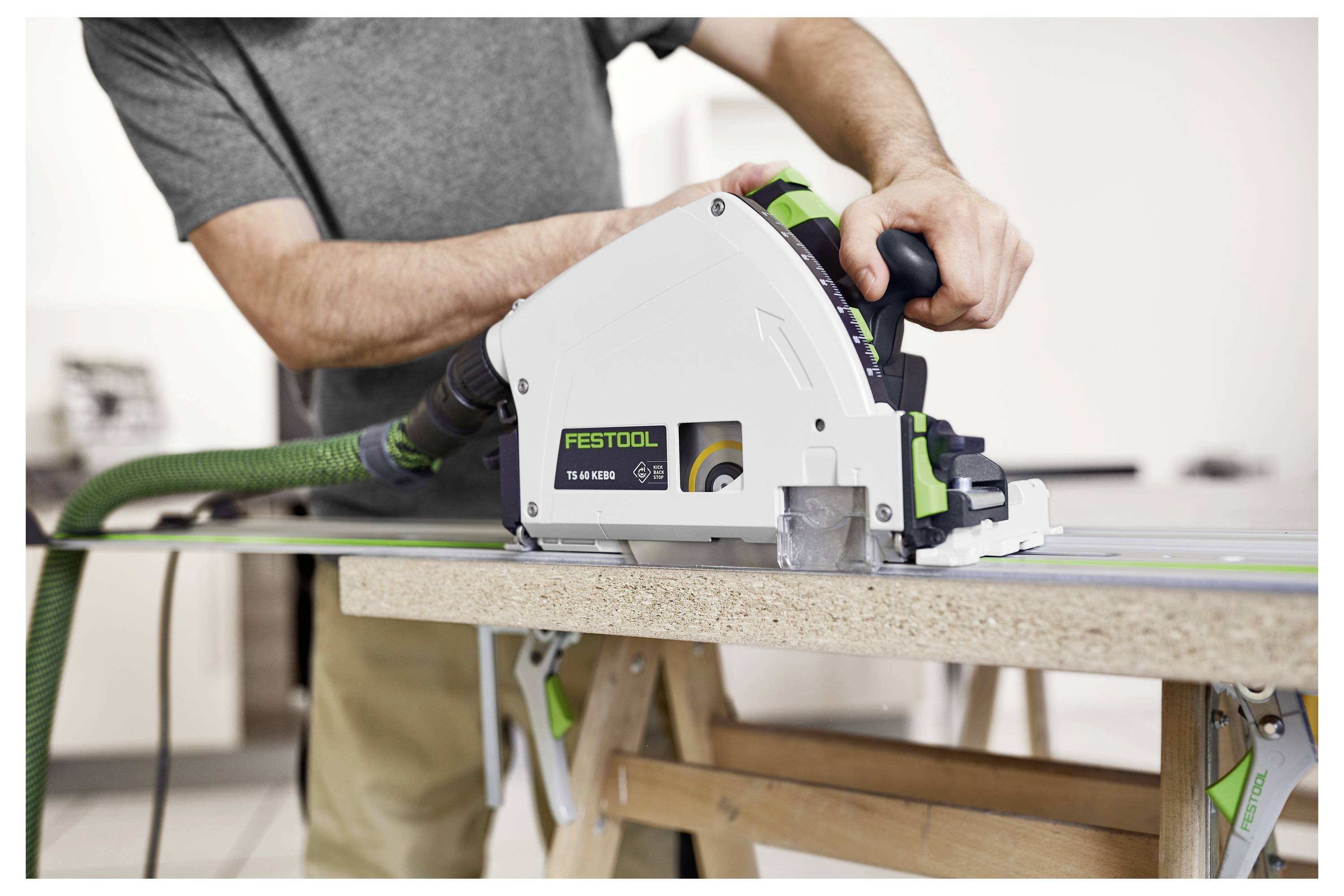 Osoba koja koristi Festool tračnu pilu za rezanje drvene daske, demonstrirajući sigurnu i preciznu tehniku obrade drva na radnom stolu.
