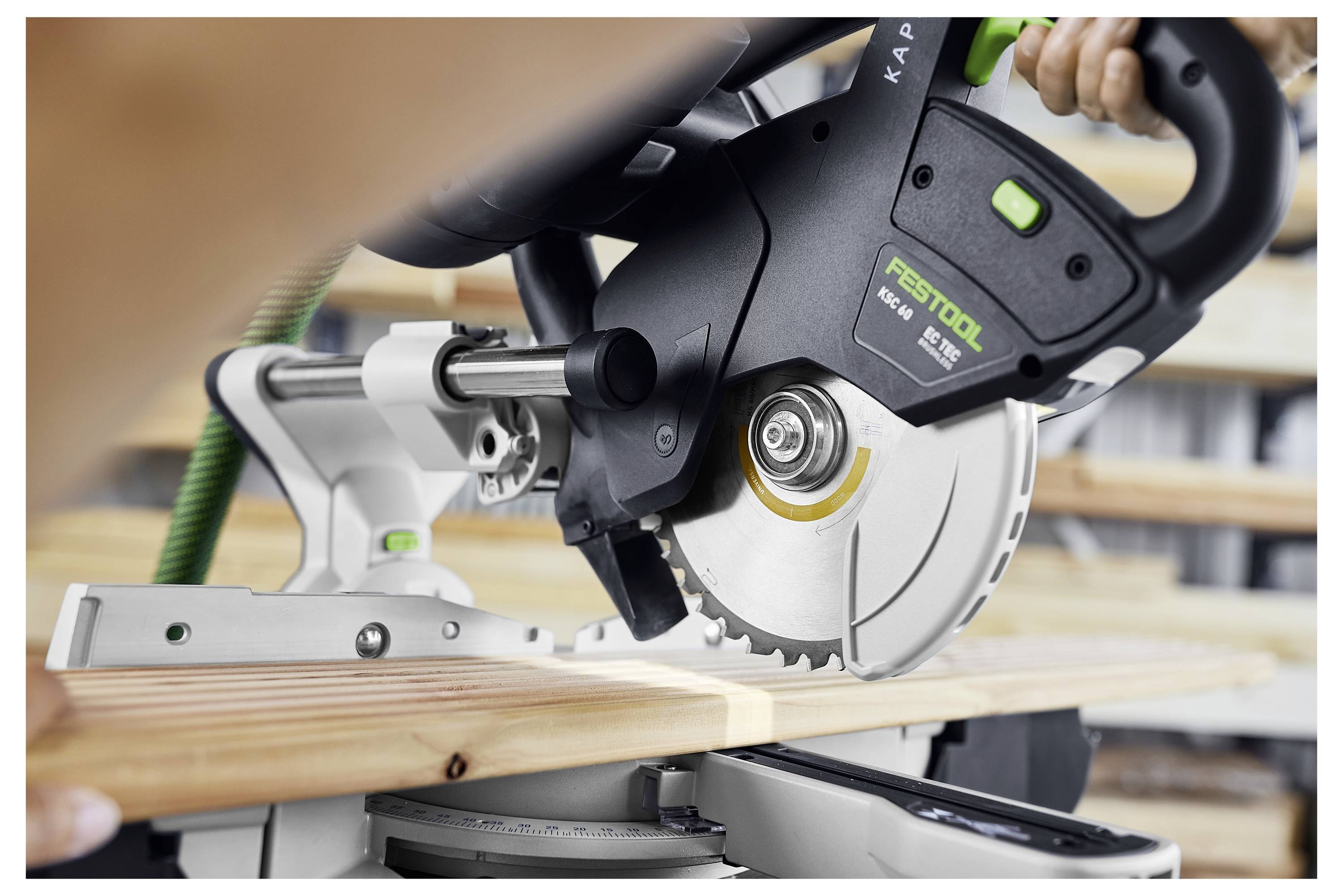 'Osoba obučena u bijele hlače i plave tenisice rukuje Festool alatom na zidu, gladeći površinu iznad tepiha na podu.'