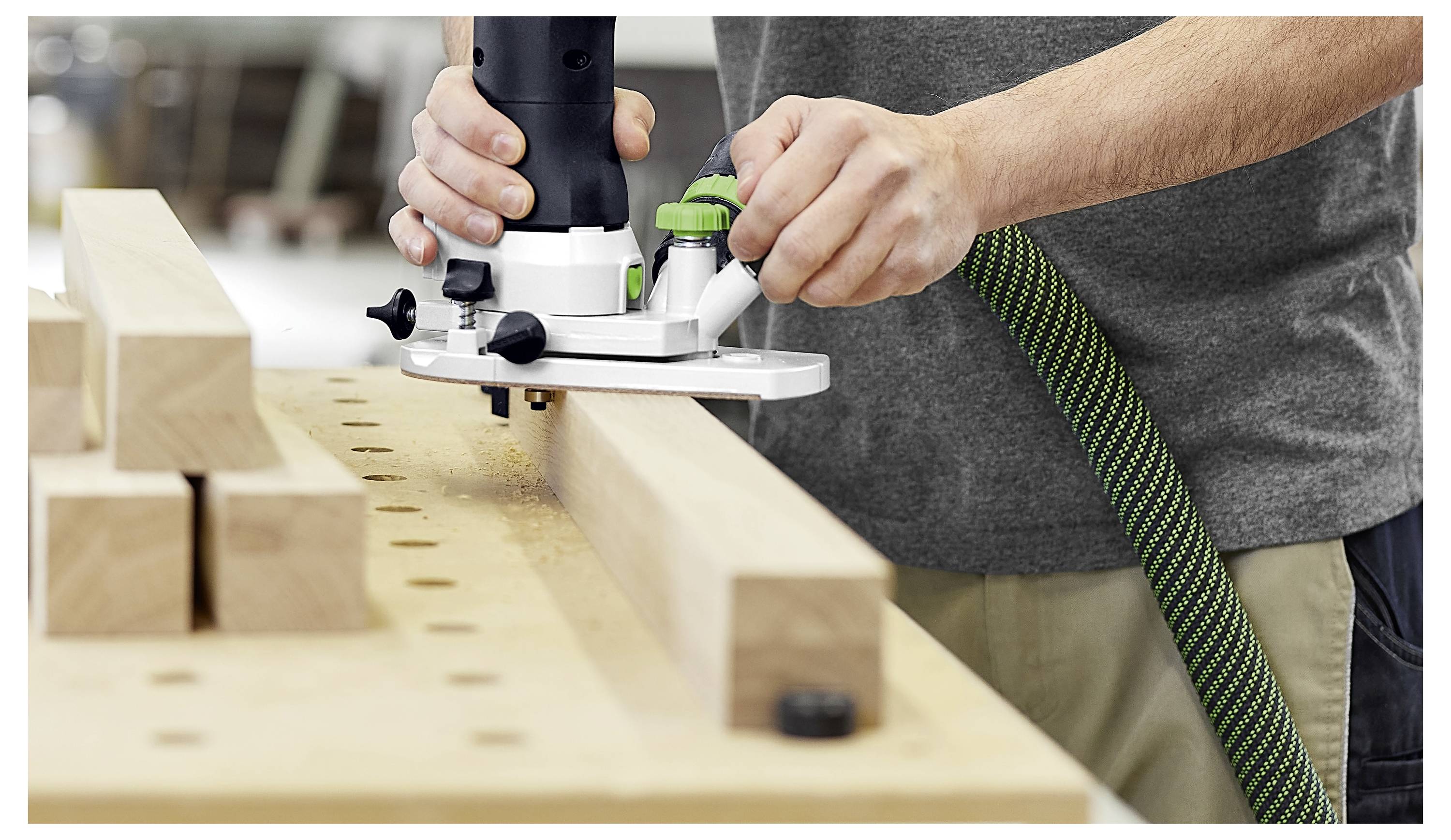 Snimka iz blizine alata za obradu drva koji obrezuje rubove drvene ploče, pokazujući preciznost reza duž površine ploče.