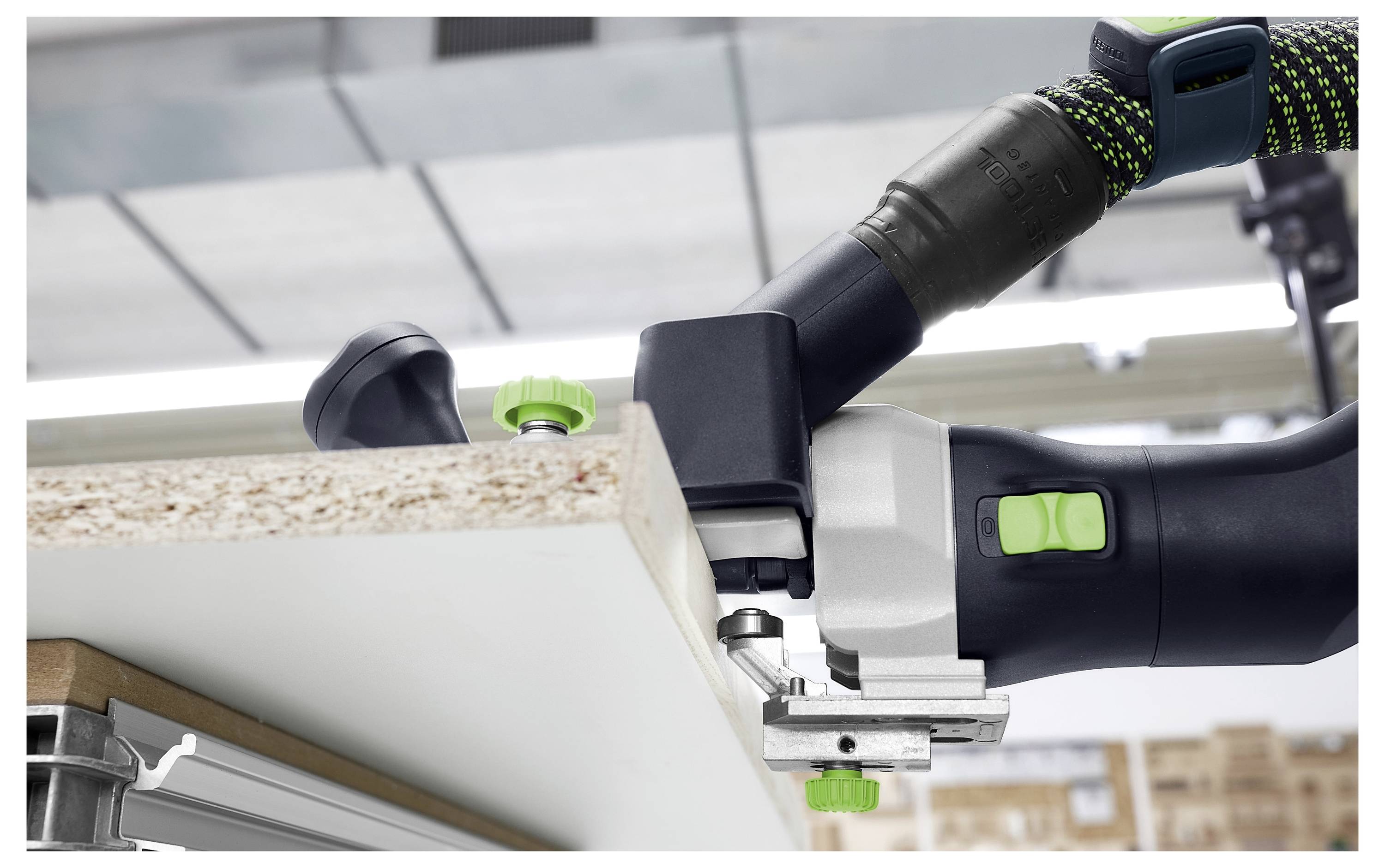 Detaljan snimak osobe koja koristi precizni alat za obradu drva kako bi izrezala žljeb na rubu bijele daske u radionici.