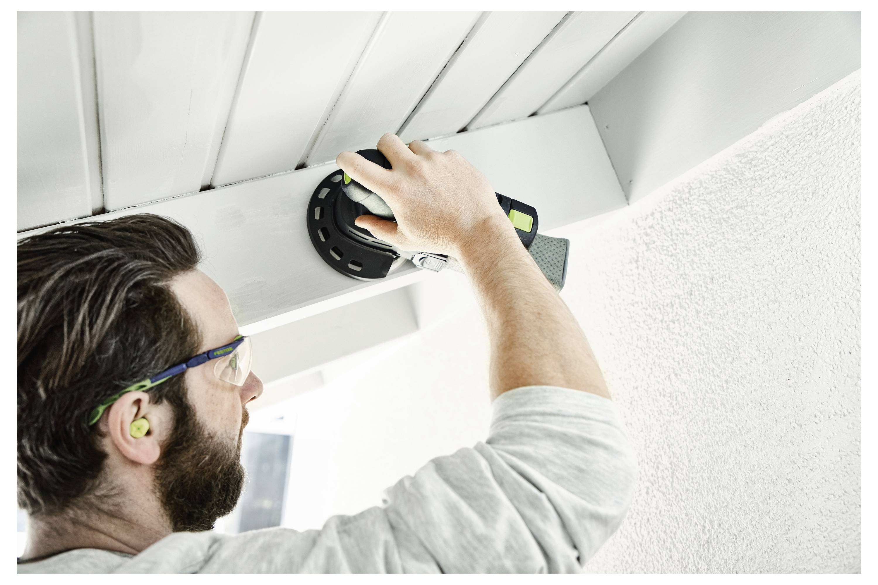 Osoba koja upravlja električnom brusilom na drvenoj površini, pokazujući pravilno postavljanje ruku za upotrebu alata i kontrolu.