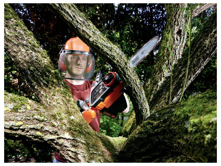 Osoba odjevena u zaštitnu opremu koristi motornu pilu za rezanje grana velikog stabla u gustoj šumskoj okolini.