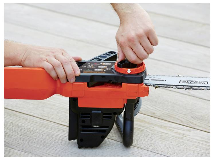 Osoba u traperama i crvenoj majici drži crvenu i crnu motorna pila na otvorenom, spremna za upotrebu na travljnatom području sa stablima u pozadini.