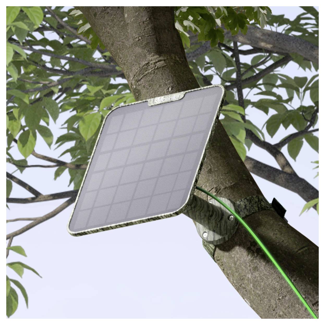 Solarni panel je montiran na grani stabla s zelenom žicom koja je priključena na njega, okružen zelenim lišćem pod dnevnom svjetlošću.