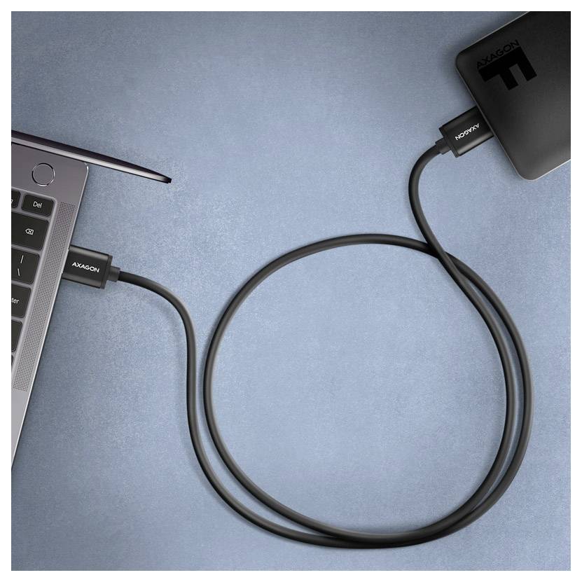 Prijenosno računalo spojeno na vanjsku powerbanku putem USB-C kabela na plavoj površini.