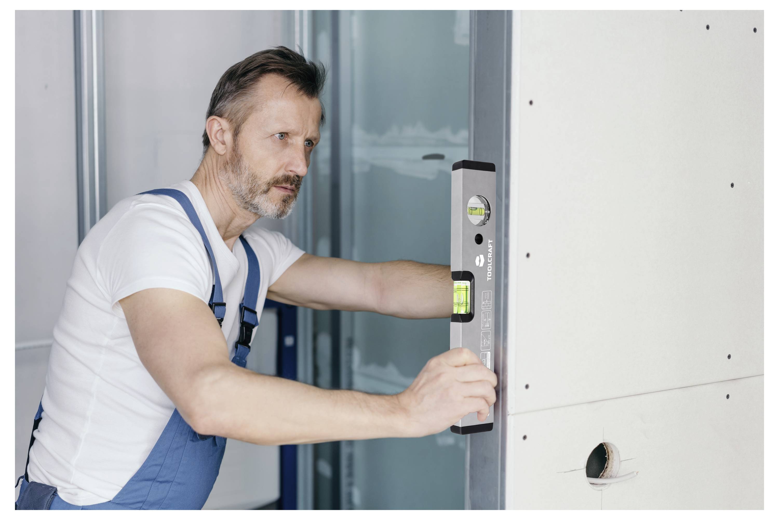 Radnik na gradilištu koristi libelu za poravnanje zidnog panela tijekom unutarnje instalacije.