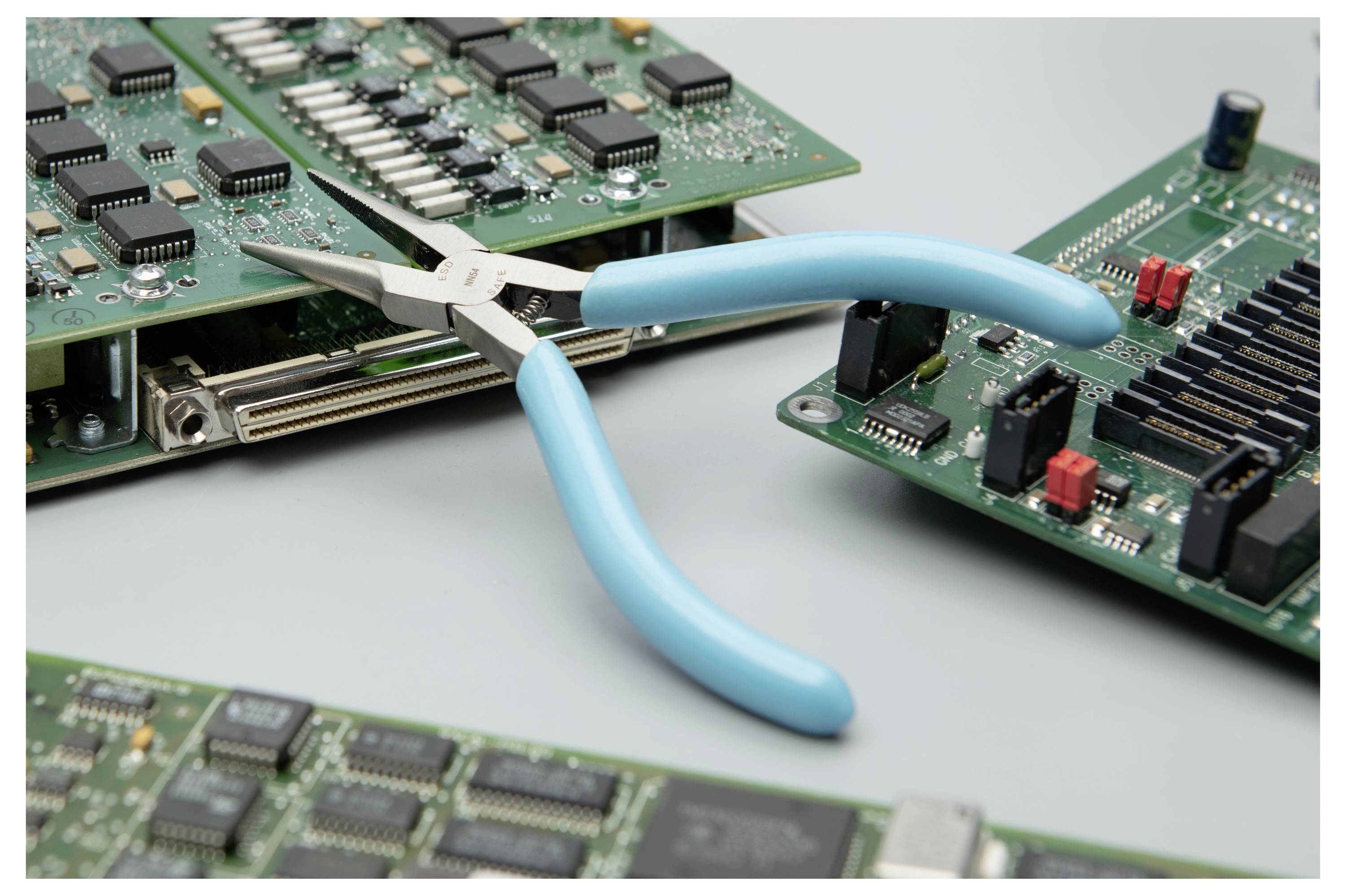 Kombinezi s plavom ručkom drže elektroničku pločicu, što sugeri reparaciju ili rastavljanje računalne opreme.