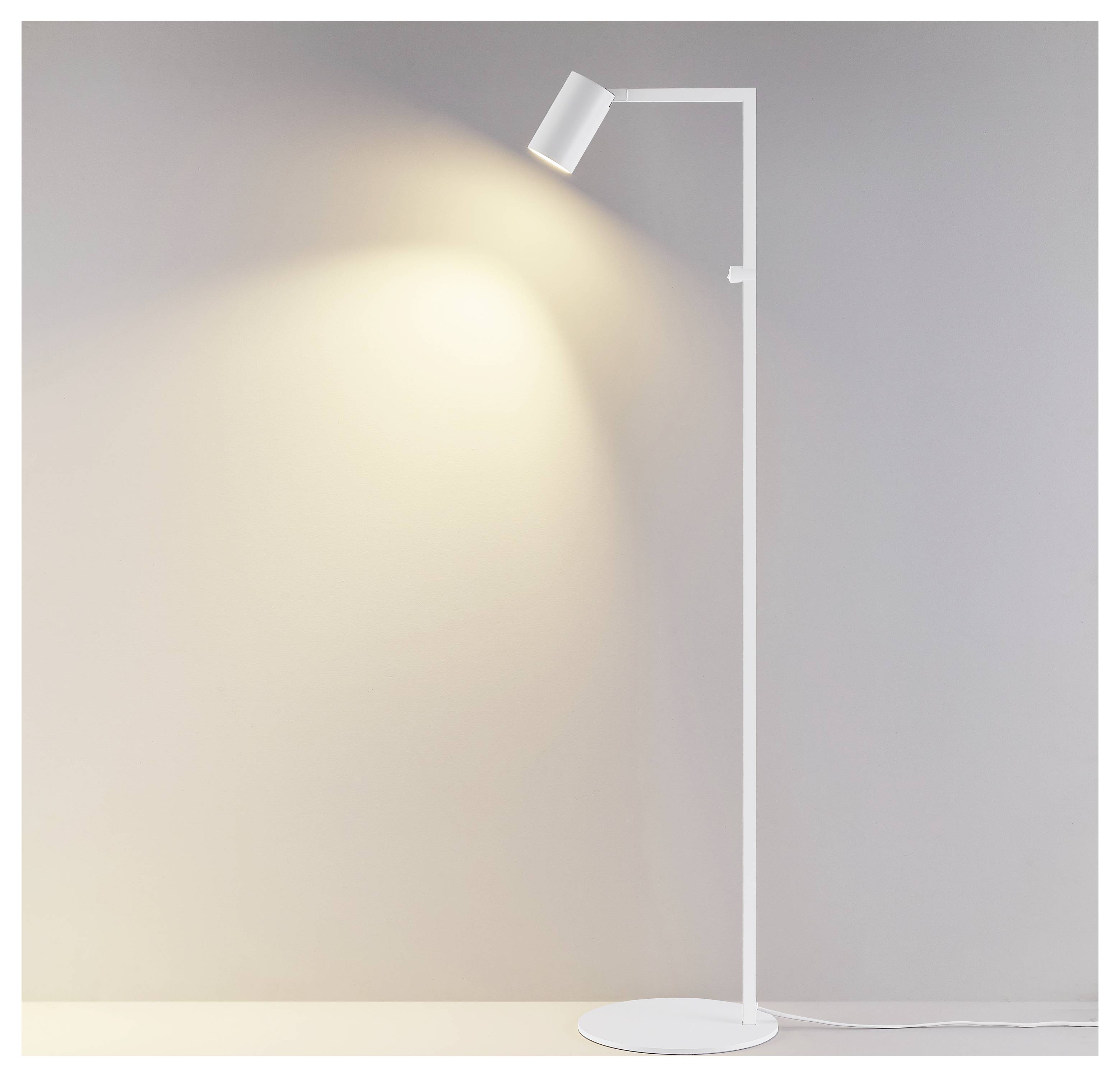 Bijela podna lampa sa reflektorom koji baca toplu zraku na sivi zid u minimalističnoj sobi.