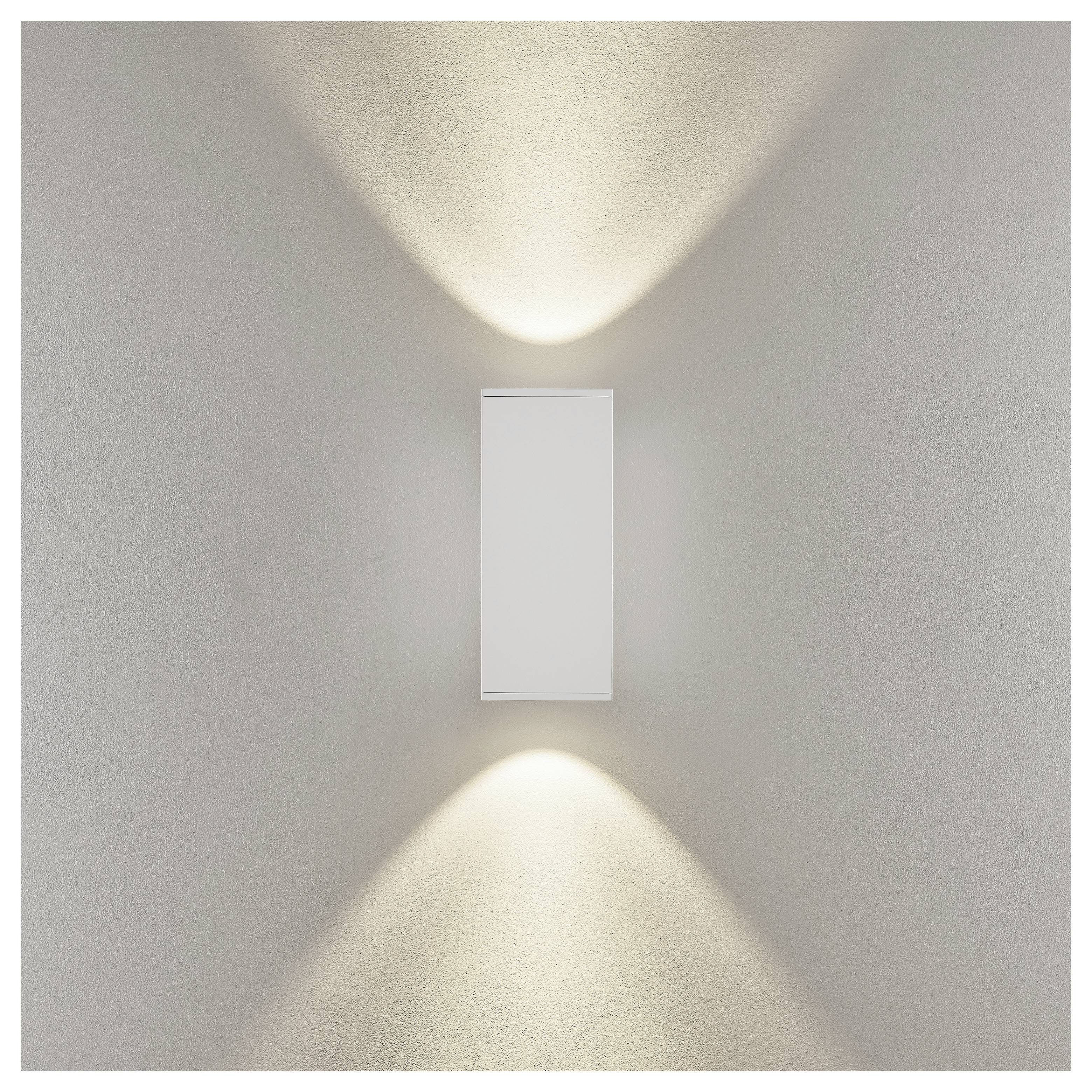 Minimalna bijela zidna lampa koja baca mekanu svjetlost gore-dolje na bež zidu.