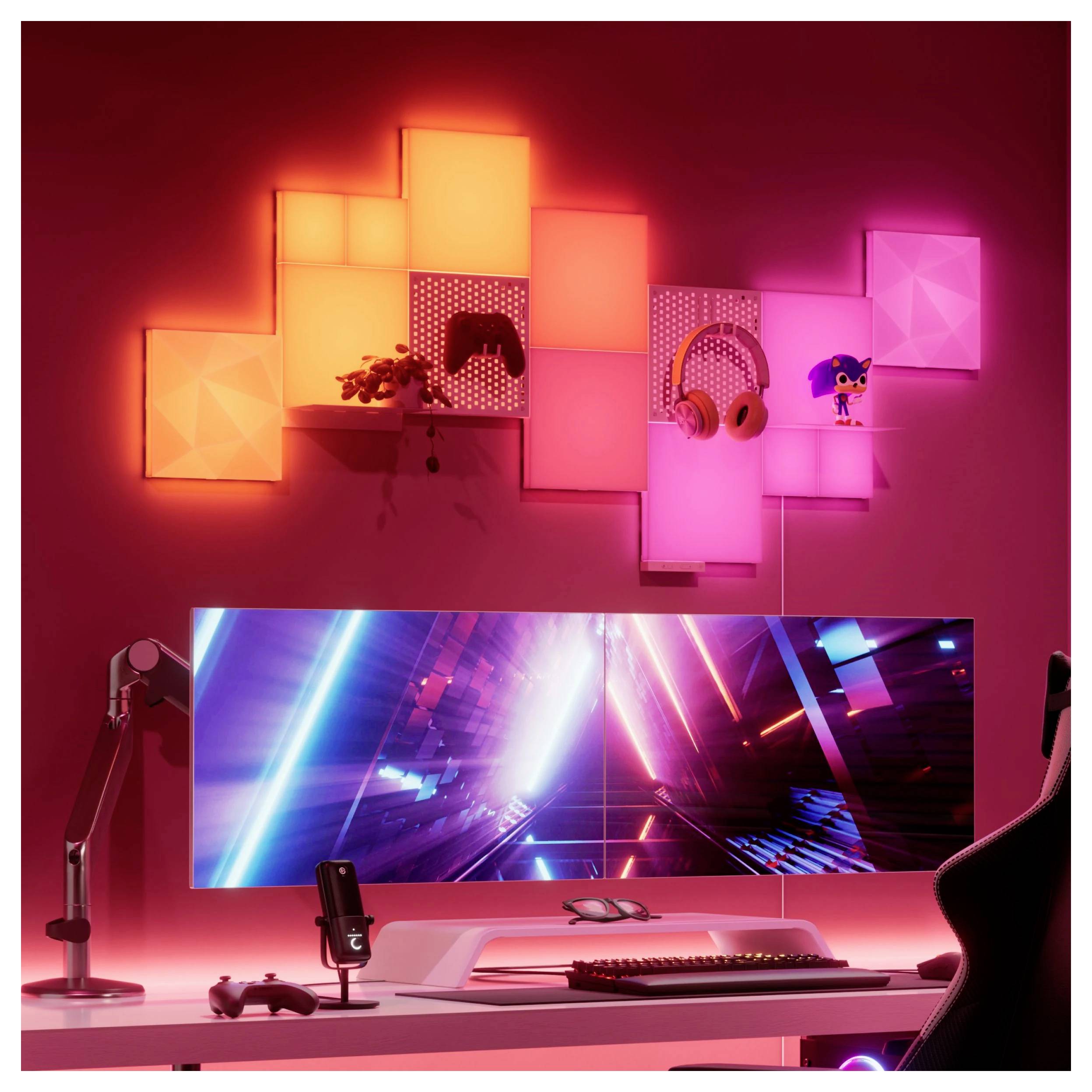 Postavka gaming stola s ultraširim monitorom, RGB osvjetljenjem, panelima na zidu, slušalicama, mikrofonom, tipkovnicom i kontrolerom u sobi s ružičastom rasvjetom.