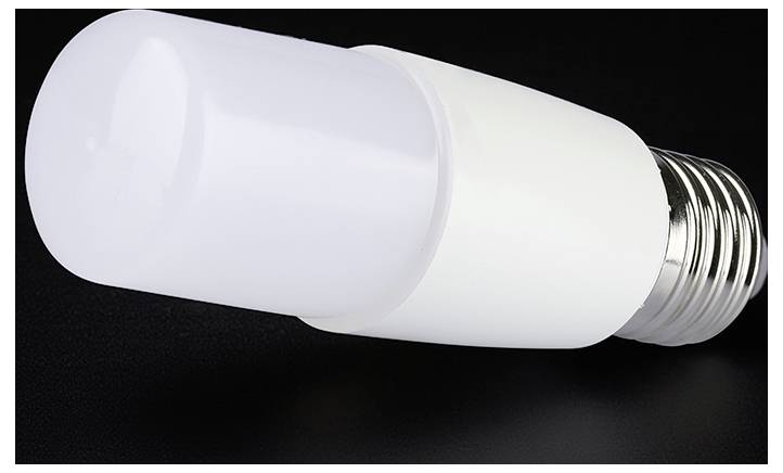 Detaljan snimak bijele LED žarulje sa zavojnom podlogom na tamnoj pozadini.