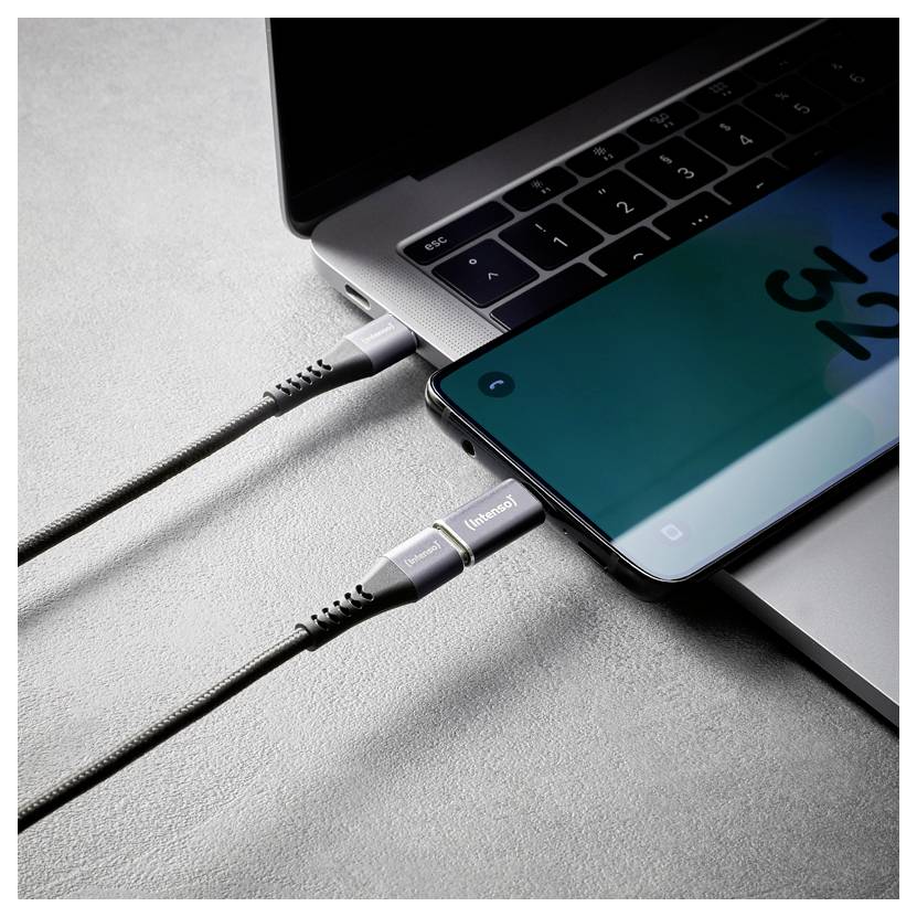 Bliskup prijenosnog računala i pametnog telefona povezanih s dva kabela, što sugeriše punjenje uređaja ili prijenos podataka.