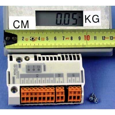 Kompaktni elektronički modul s priključnim konektorima prikazan je pored ravnala i digitalne vage koja pokazuje 0,05 kg, što ukazuje na njegovu veličinu i težinu.