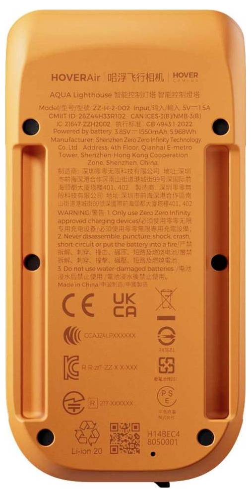 Donja strana Orange HOVERAir AQUA drona s ispisanim regulatornim oznakama, modelom i certifikacijskim oznakama, pretincem za bateriju i četiri crne točke za montažu/vijke.