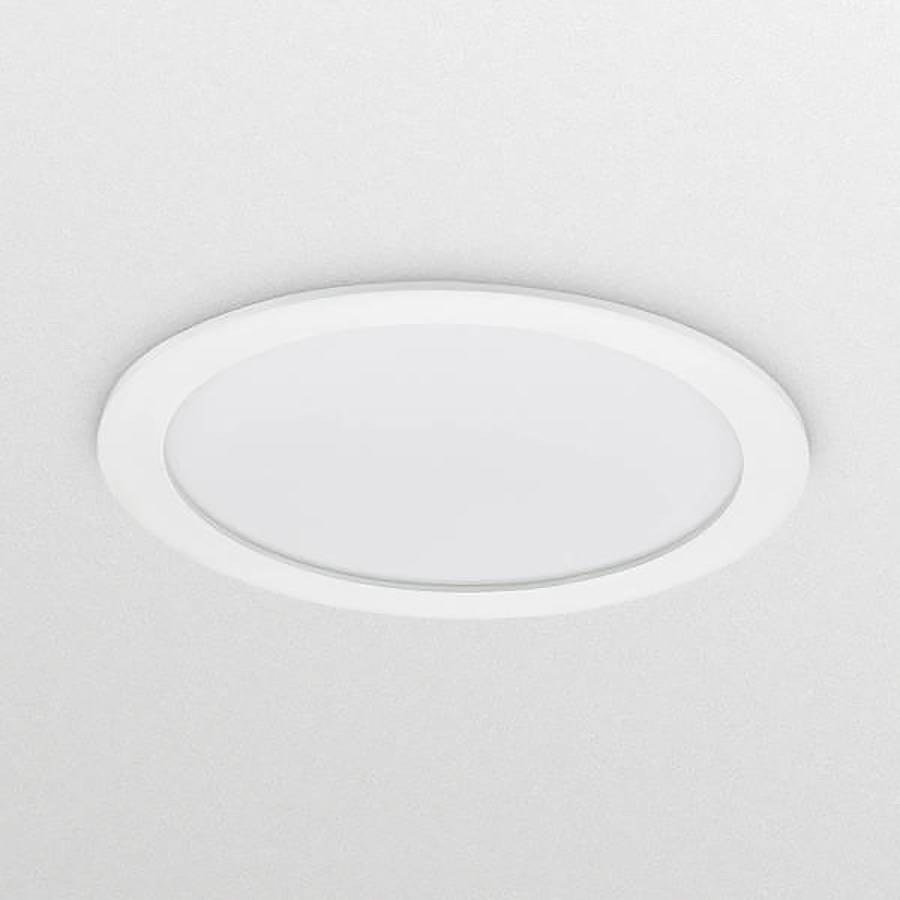 Okrugla bijela uronjena stropna lampa na svijetlo sivo-plavičastom stropu, gledano odozdo.