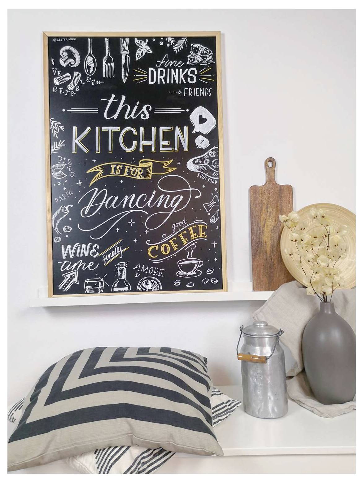 Uklonjeni kuhinjski znak od krede s tekstom 'THIS KITCHEN IS FOR Dancing' s riječima o pićima, vinu, kavi i prijateljima na polici s dekoracijom.