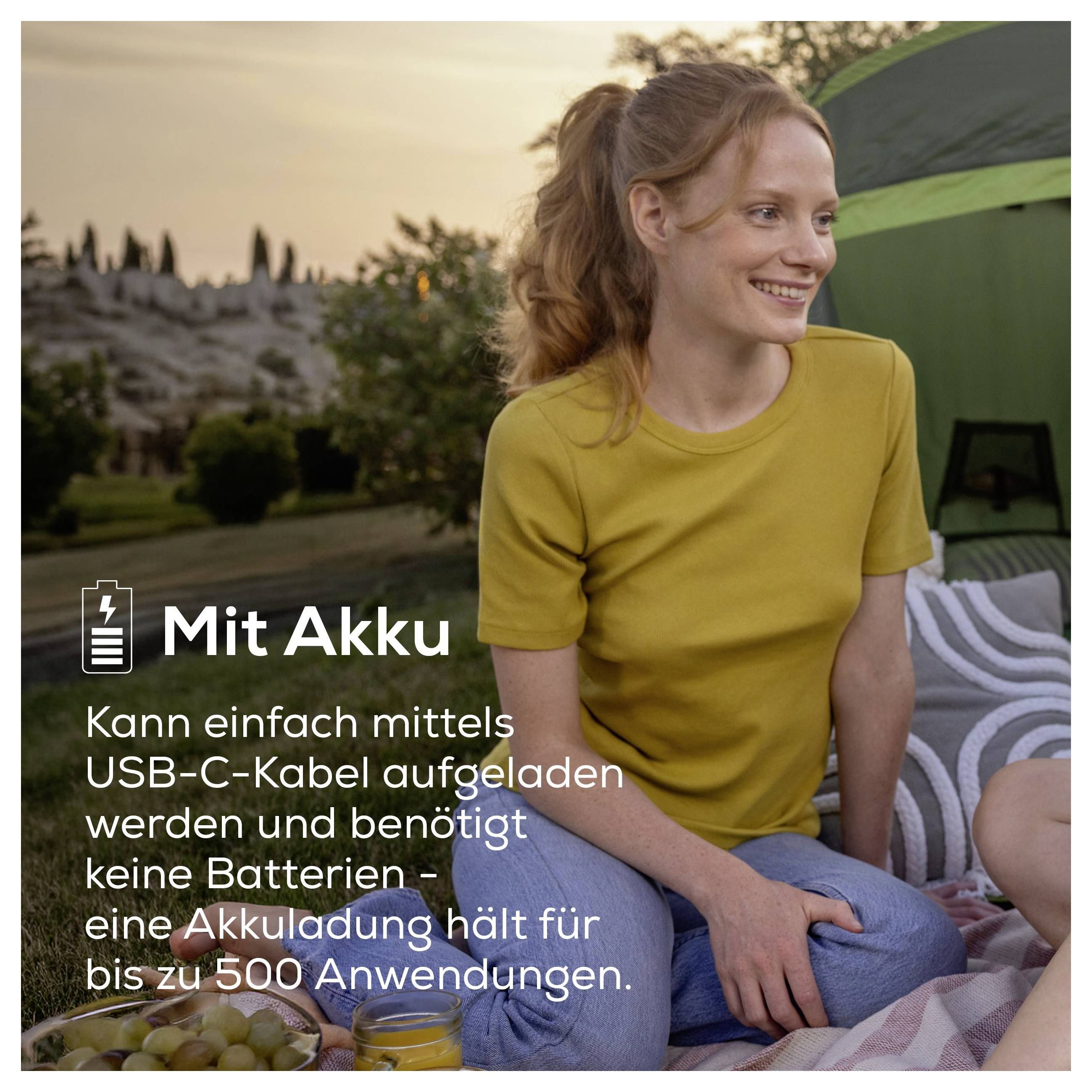 Reklamen fotografija žene u šatoru pri zalazu sunca sa tekstom: 'Sa baterijom'. Napomena: ponovno nabijivo putem USB-C, bez baterija, do 500 primjena.