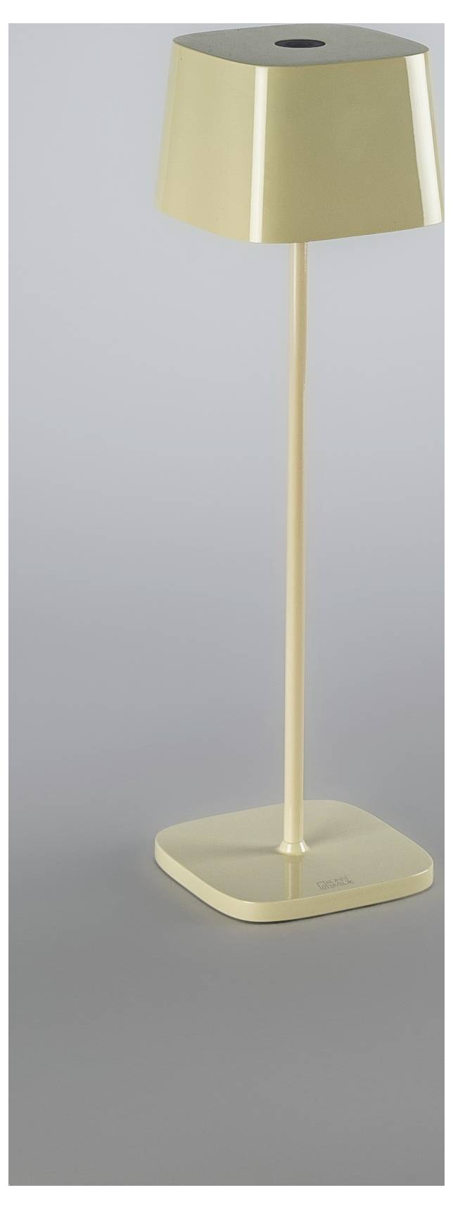 Zlatna bežična stolna lampa sa suženom abažurom i kvadratnom bazom na jednoličnoj sivoj pozadini
