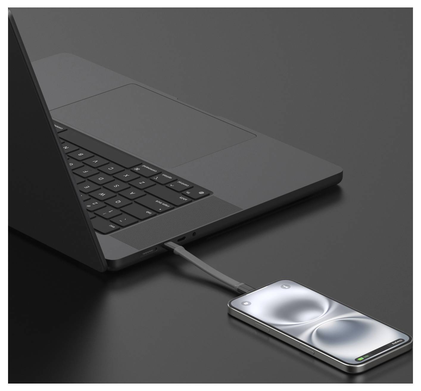 Prijenosno računalo spojeno kablom na pametni telefon koji prikazuje indikator punjenja na tamnoj površini.