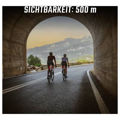 Dva biciklista voze kroz tunel na krivudavoj cesti; na vrhu piše 'VIDLJIVOST: 500 m'.