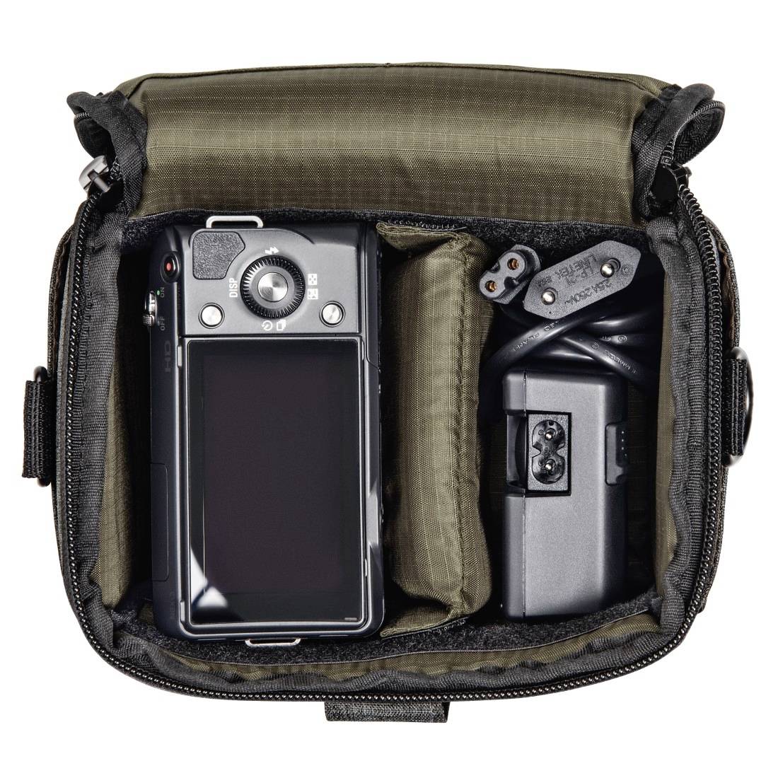 Otvorena torbica za kameru s tijelom mirrorless kamere, punačem, baterijom i kablovima uredno organiziranim u pjenjastim pretincima.