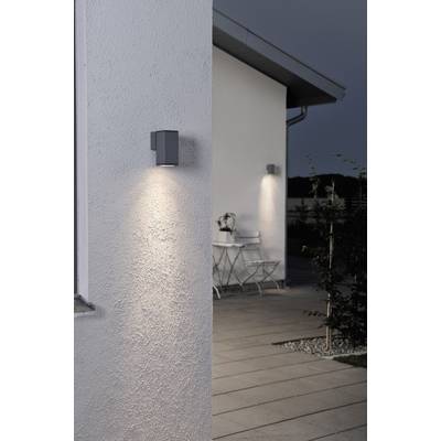 Vanjski pogled na kuću u sumrak sa dvije zidne lampe i stolom s stolcima u pozadini. Osvjetljen put vodi do njih.