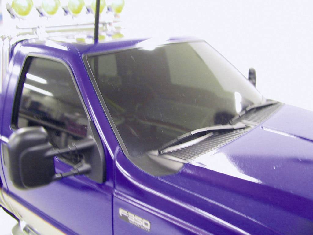 Detaljan model ljubičastog pick-up kamiona sa zrcalnim prozorima i srebrnim detaljima na krovu.