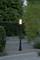 Vrtna lampa toplo svijetli u prostoru ograđenom drvećem s kamenjem, betonski blokovi u prvom planu.