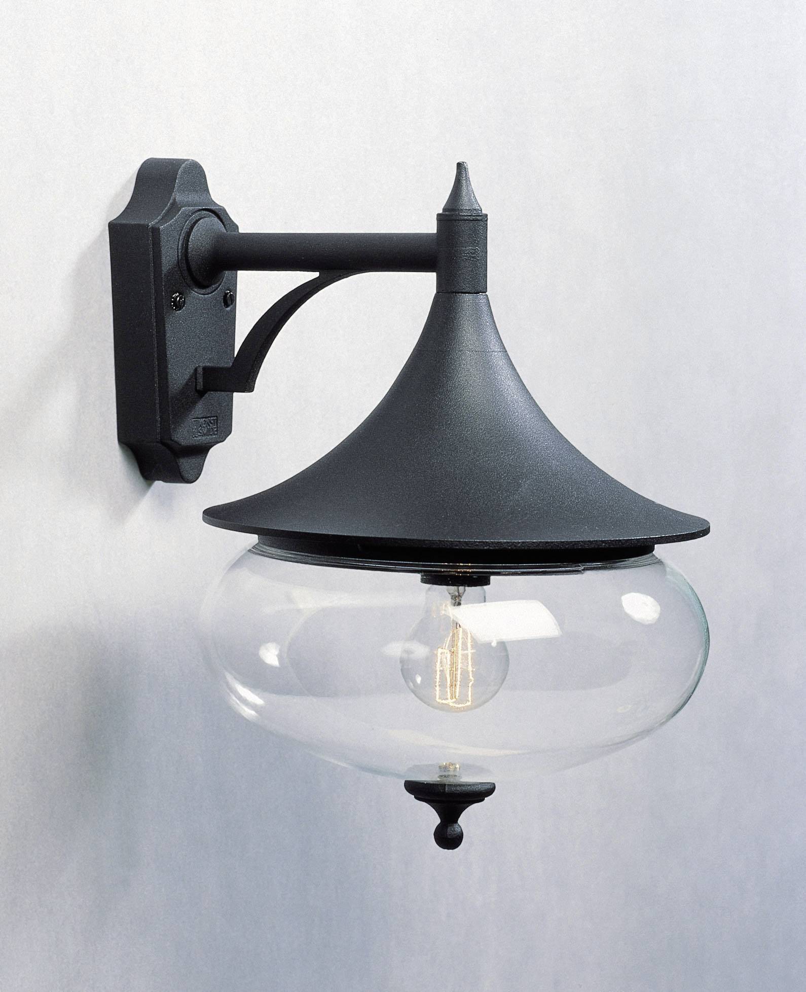 Crna lampa montirana na vanjskom zidu s prozirnim staklenim kućištem otkriva vidljivu žarulju.