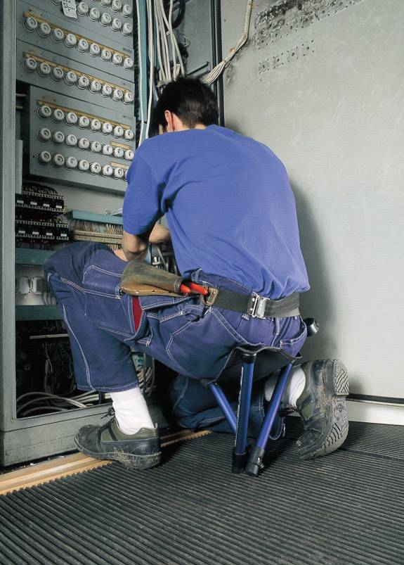 Električar radi na otvorenom razvodu, okružen raznim kablovima i sklopkama.