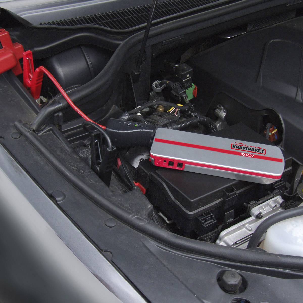 Prostor motora automobila s uređajem za paljenje koji je spojen na bateriju. Uređaj sigurno leži na poklopcu baterije.
